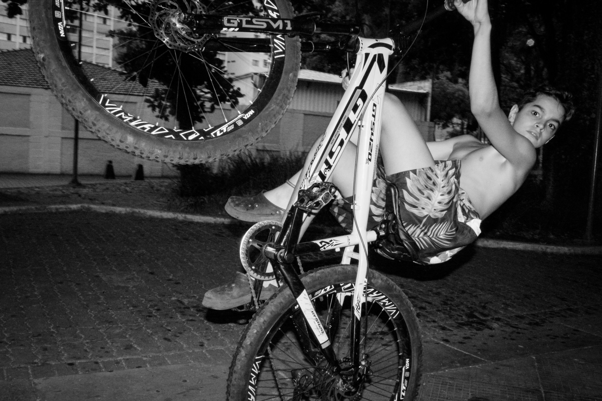 boy doing tricks on the back wheel of a bike in a car park