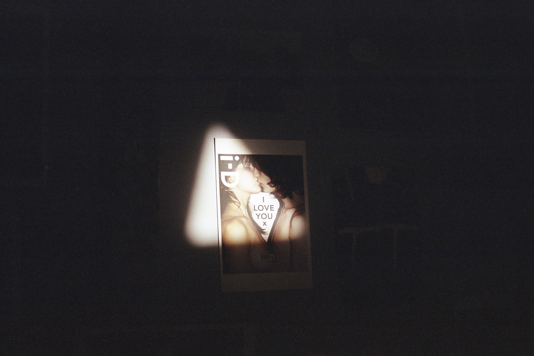 Poster of an i-D magazine cover against a blank wall and lit by a triangle of light.