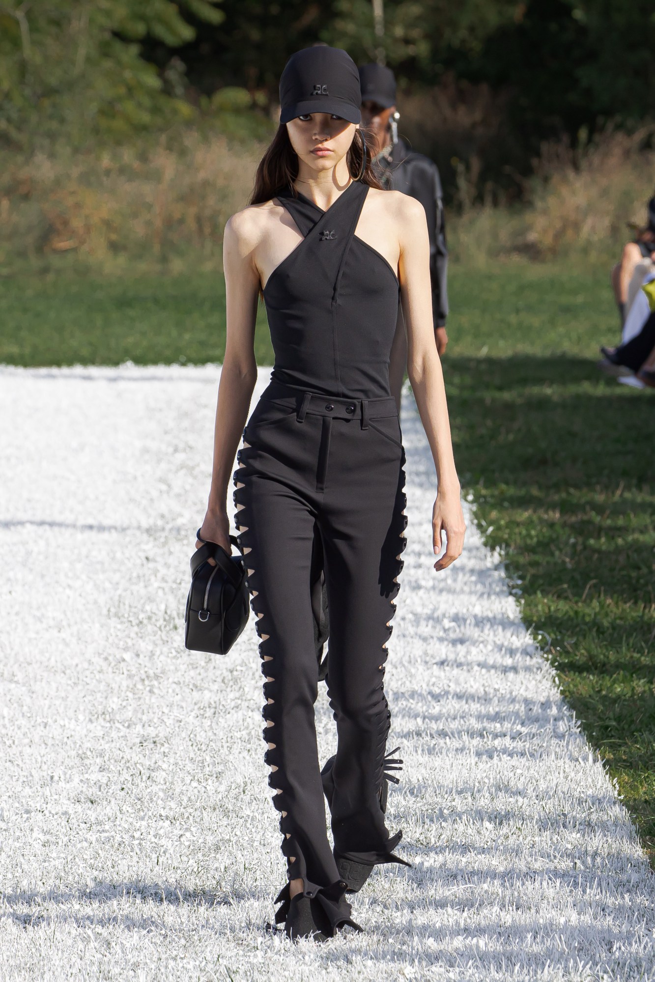 Courreges SS22 catwalk look: a model wears black trousers with cut out details and a halter top