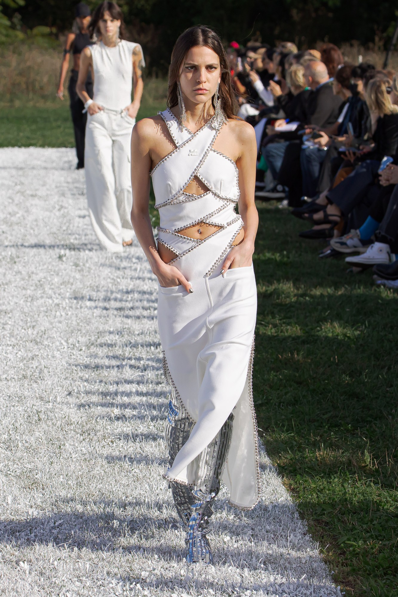 Courreges SS22 catwalk look: a model wears silver boots with a white cut-out strap detail top