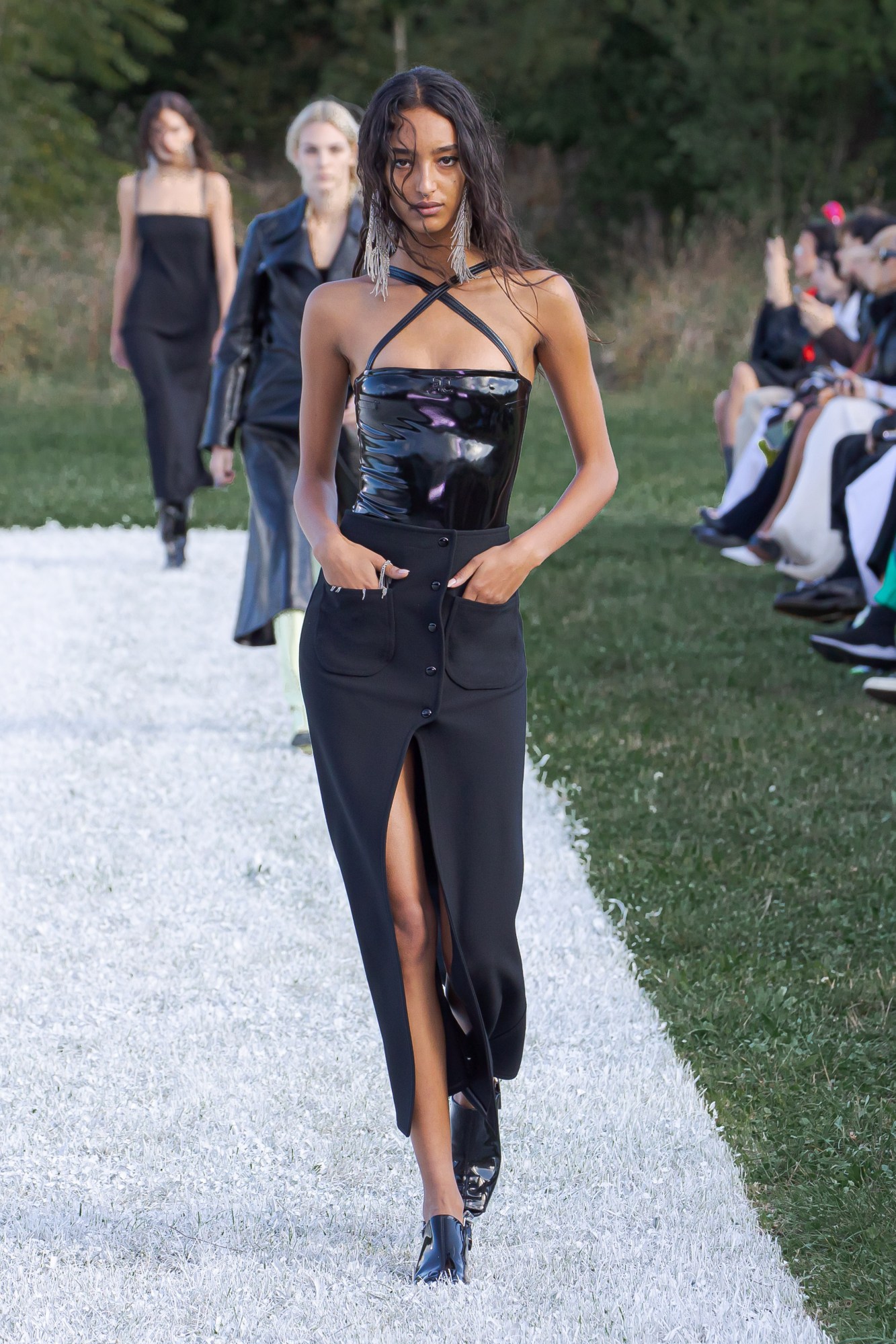 Courreges SS22 catwalk look: a model wears a long black pencil skirt with a slit, with a PVC halter bodice