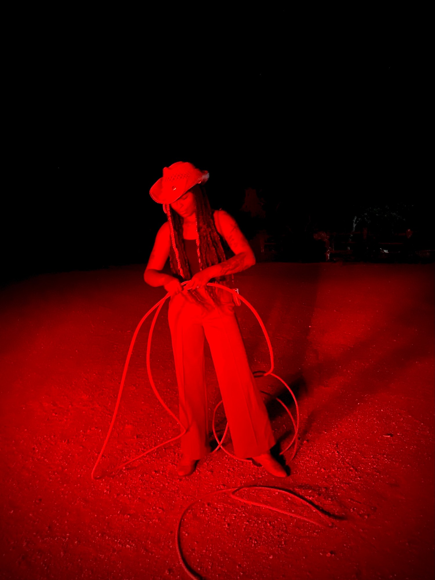 Woman putting together a lasso outside under a red light.