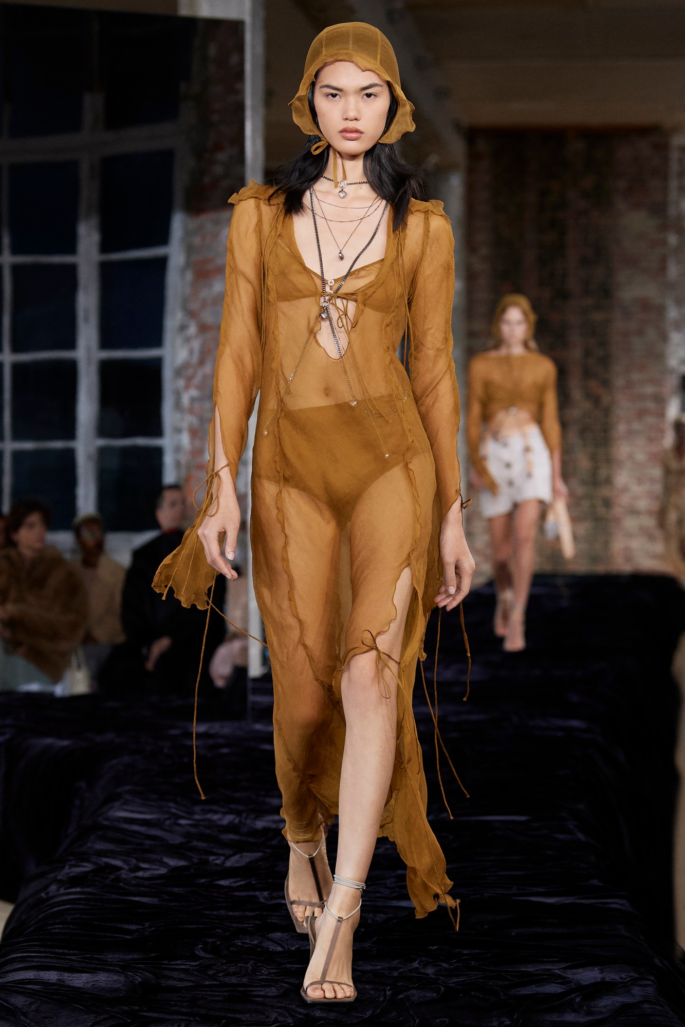 Acne Studios SS22: a model wears a sheer floaty brown dress with a matching bonnet