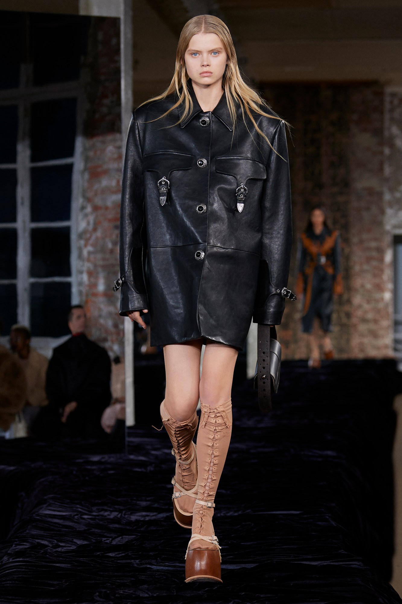 Acne Studios SS22: a model wears an oversized leather coat with chunky nude heels