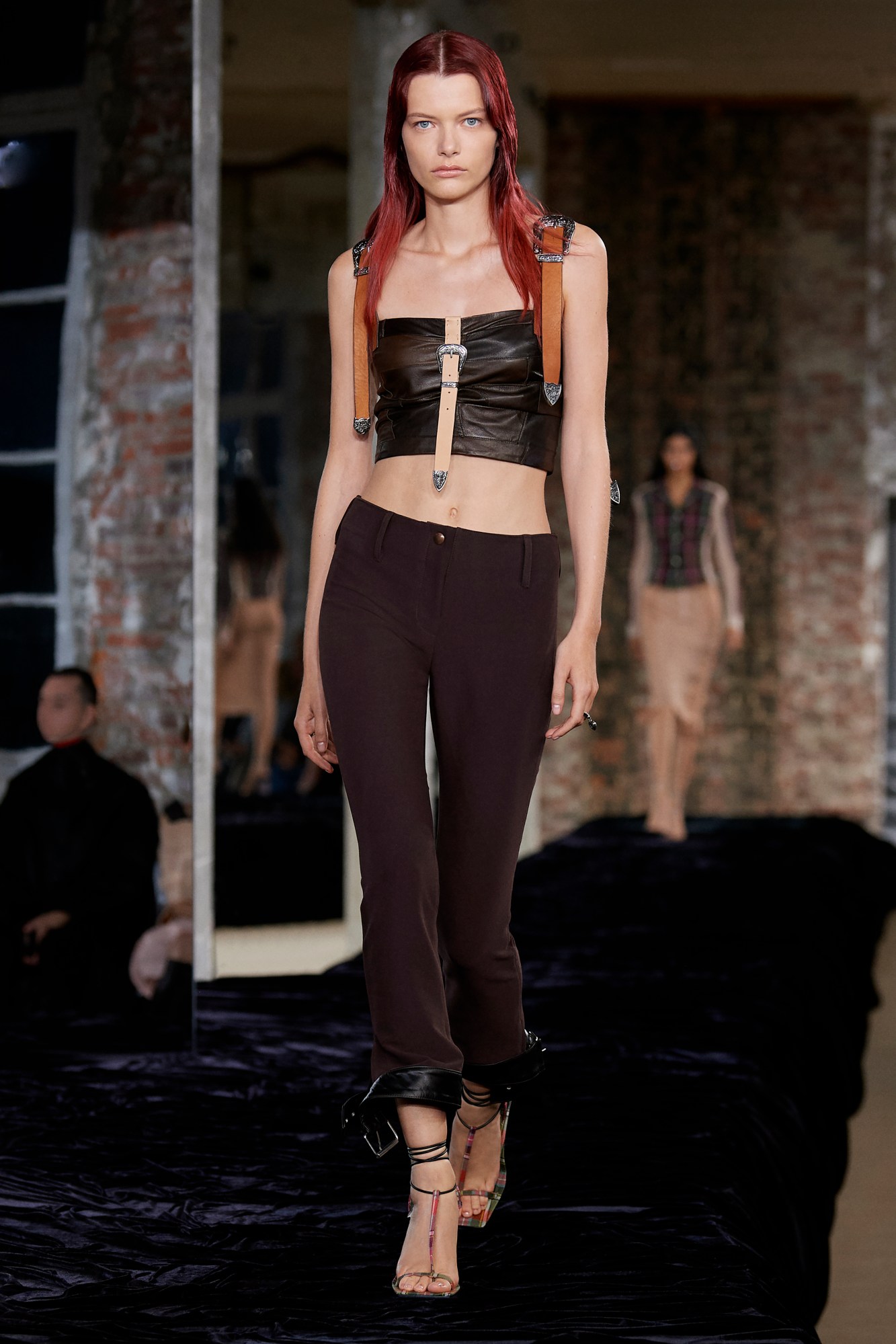 Acne Studios SS22: a model wears brown trousers with a brown patchwork leather bodice