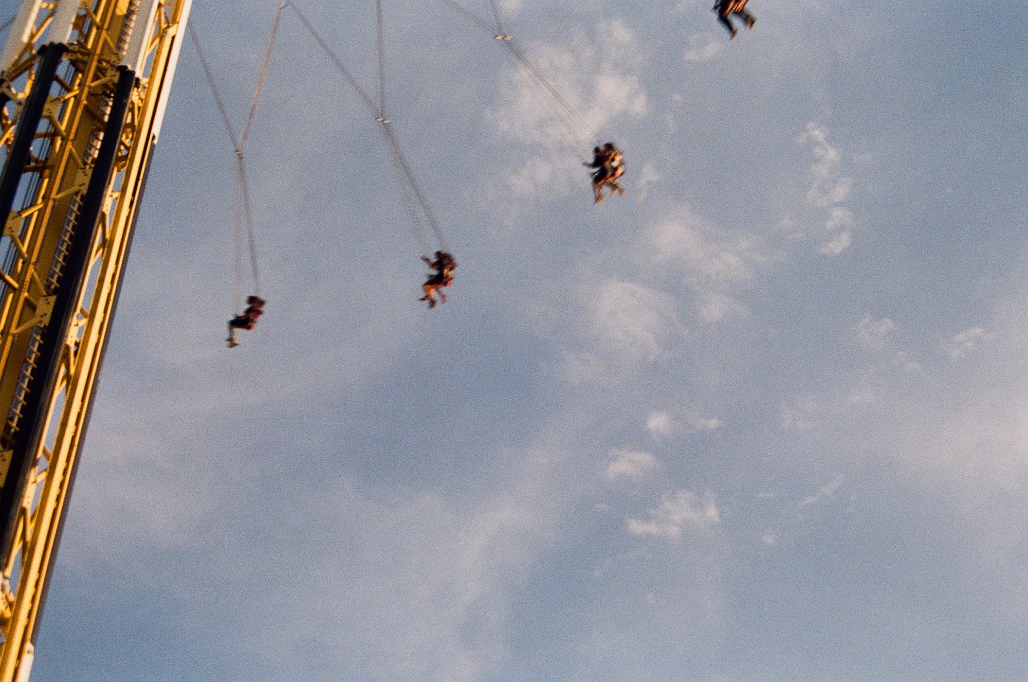 shot from below a fair ground ride that swings people around.