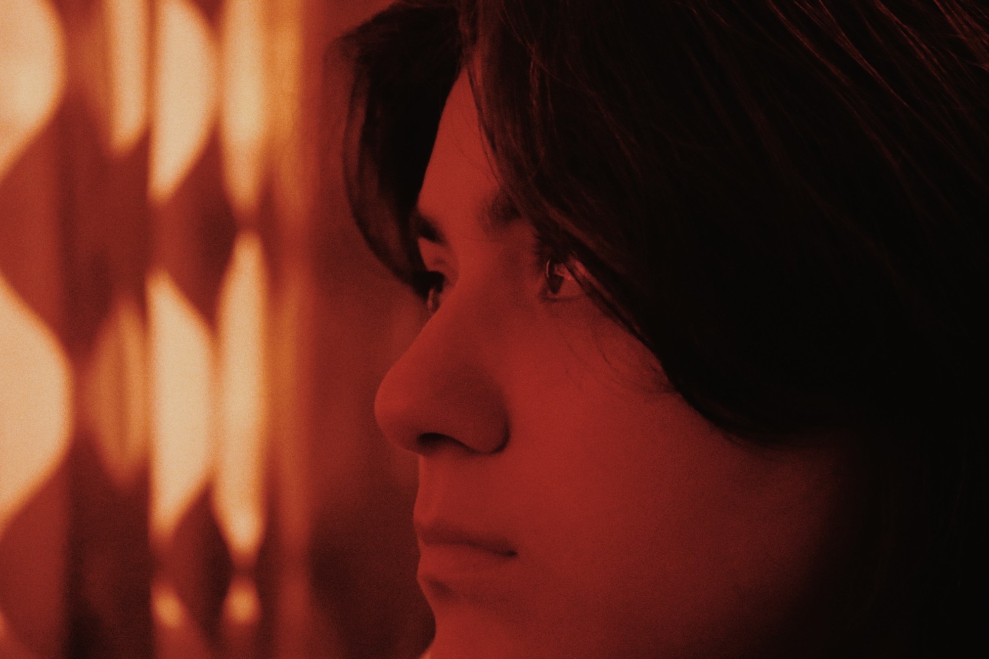 close up of a woman's face with an orange light.