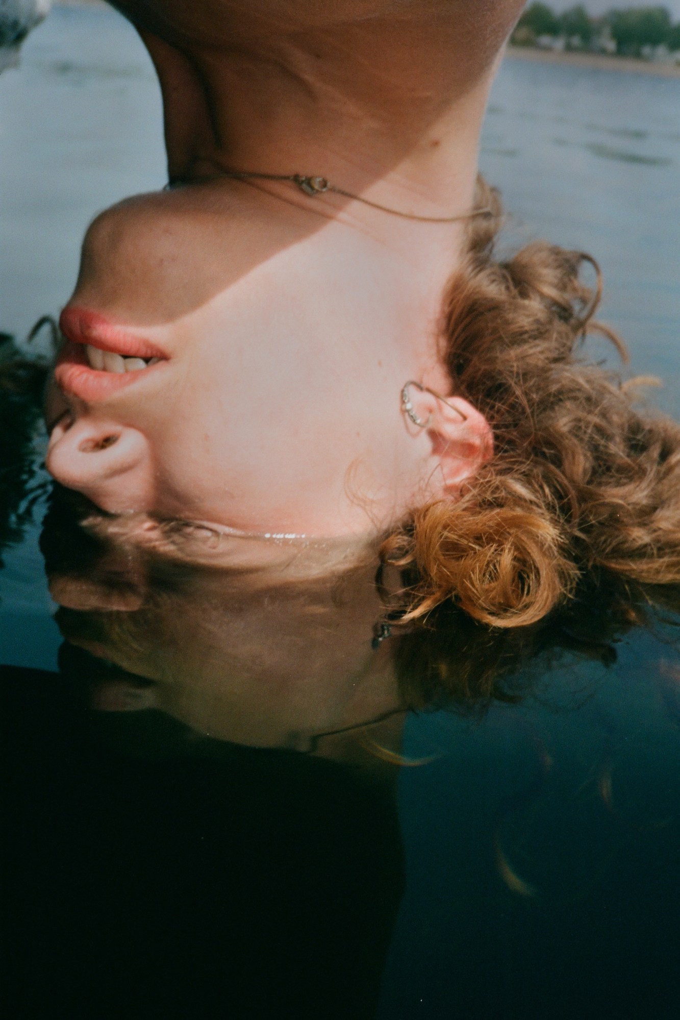 A person does a hand stand, the top of their head in the water.