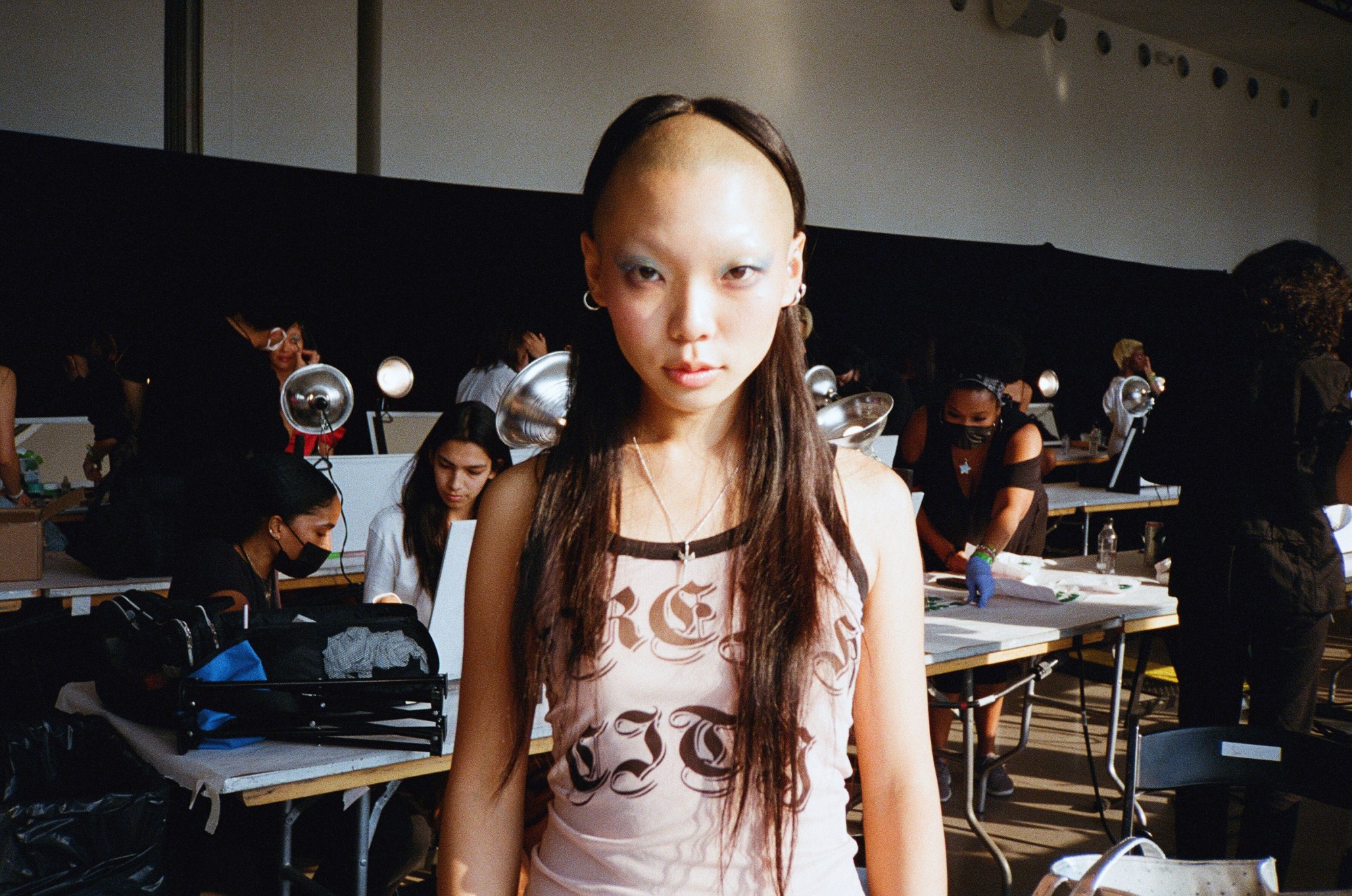 Model stands centre frame while people are designing around her.