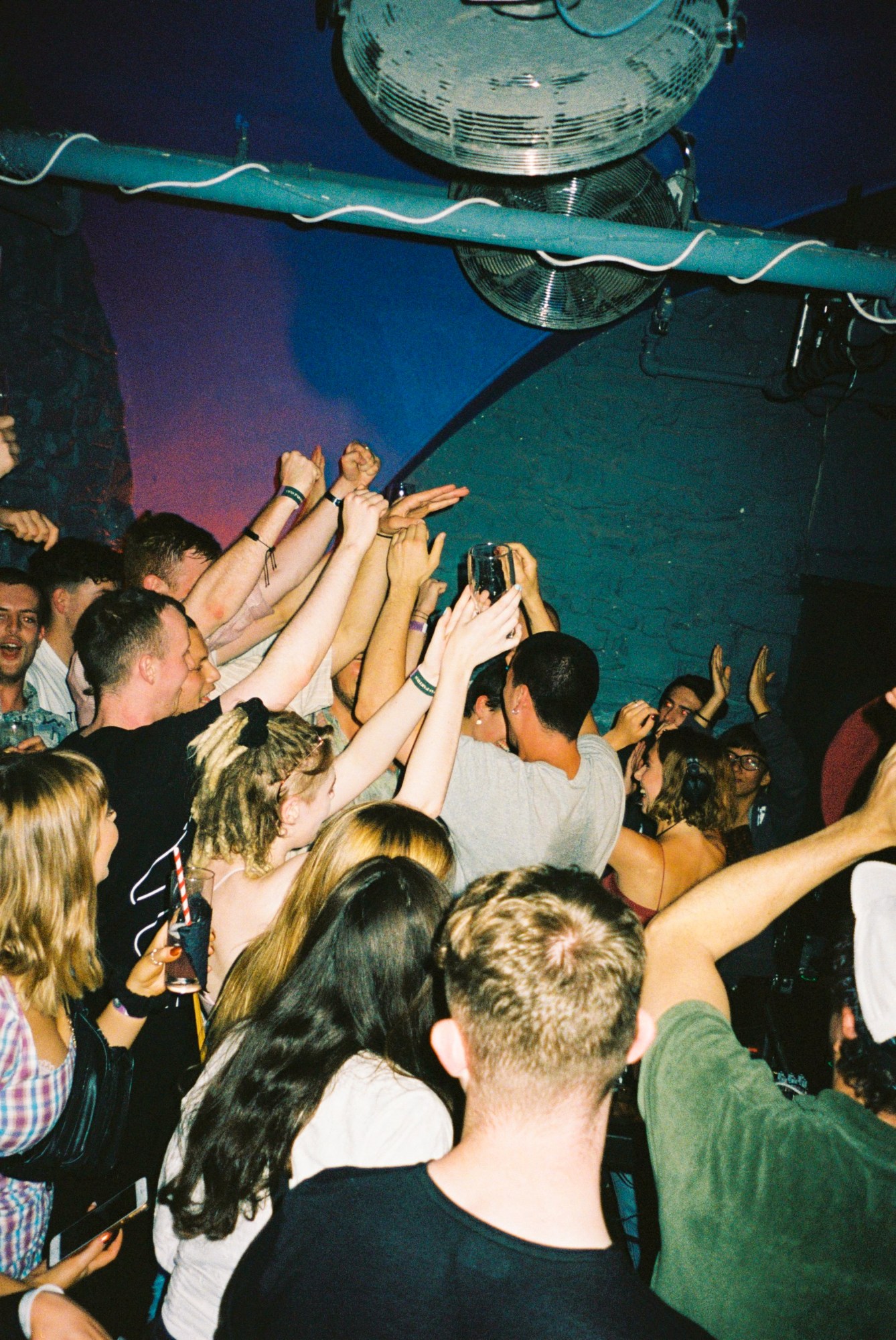 a flash photograph of the backs of people in a club, arms raised