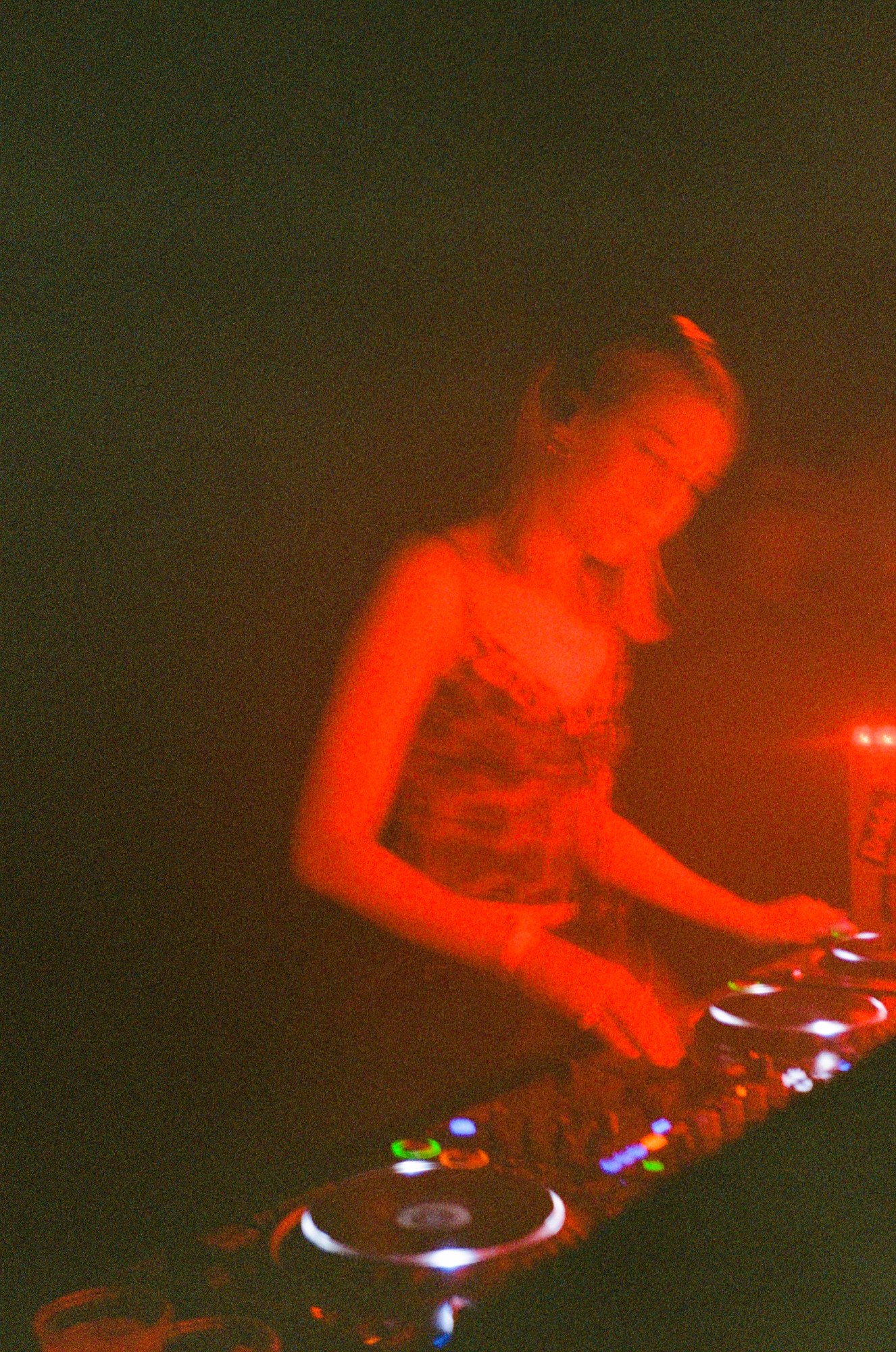 a woman bathed in red light is djing