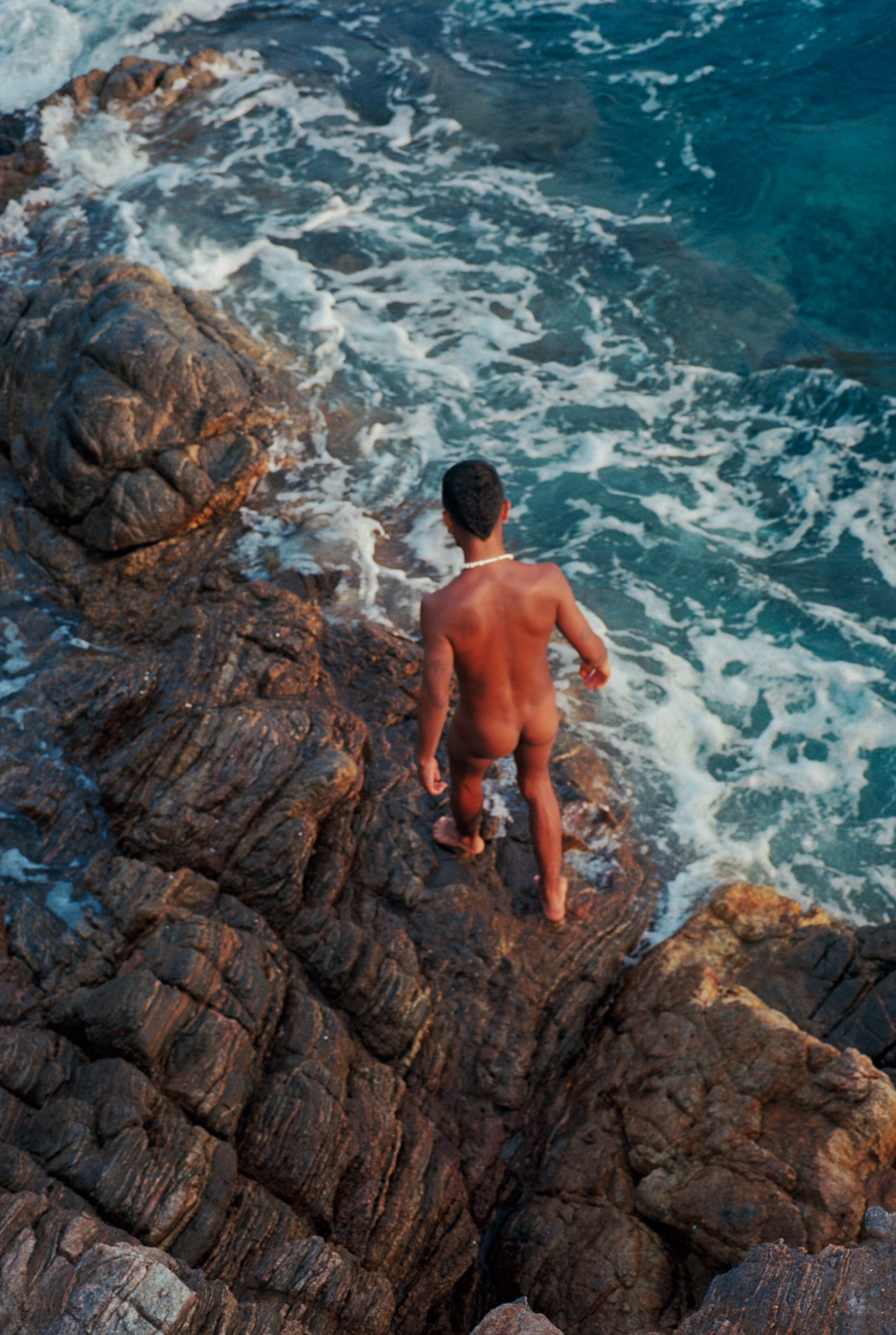 a man walks towards the sea over rocks naked in mexico