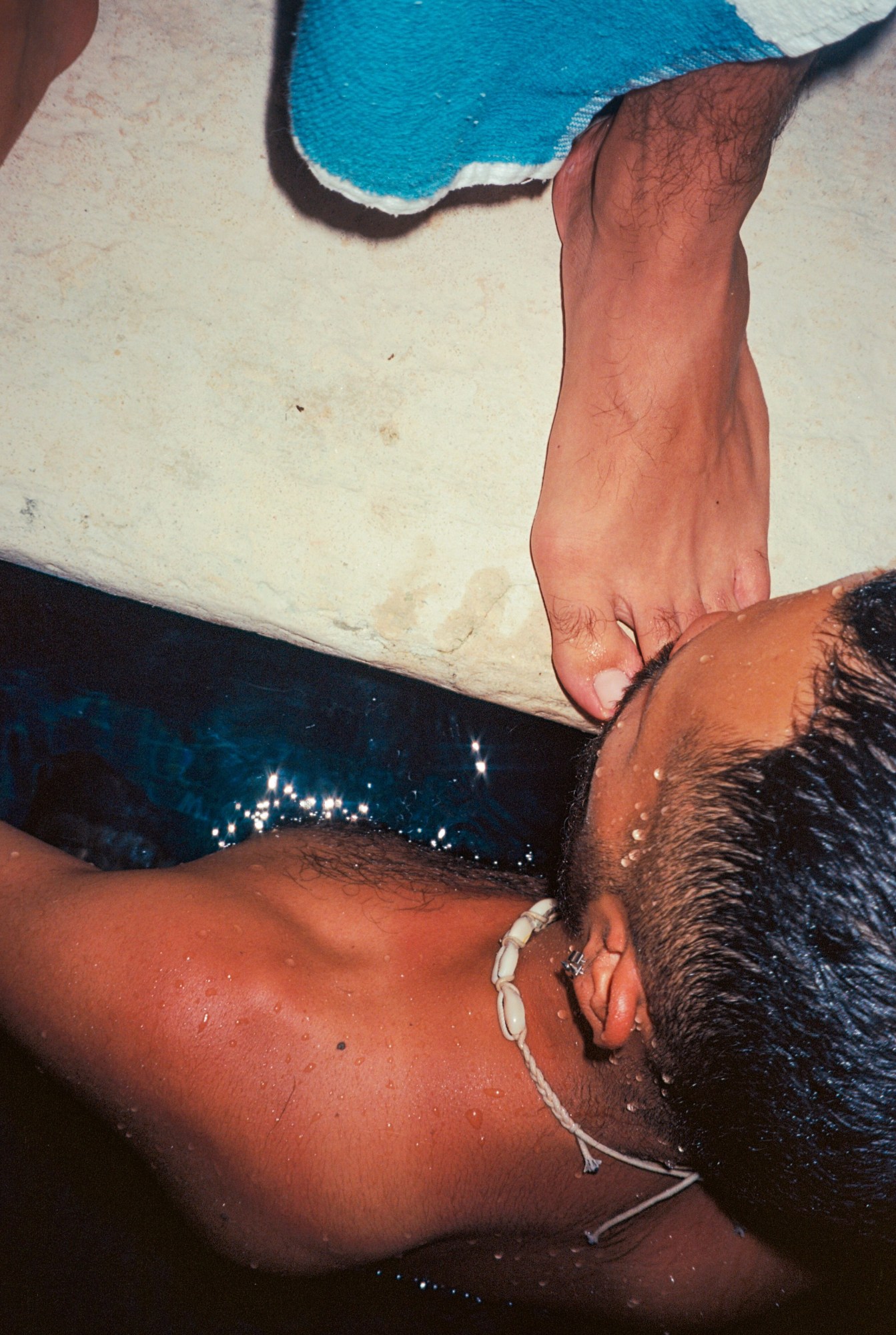 a man in a pool kisses the foot of someone standing beside it