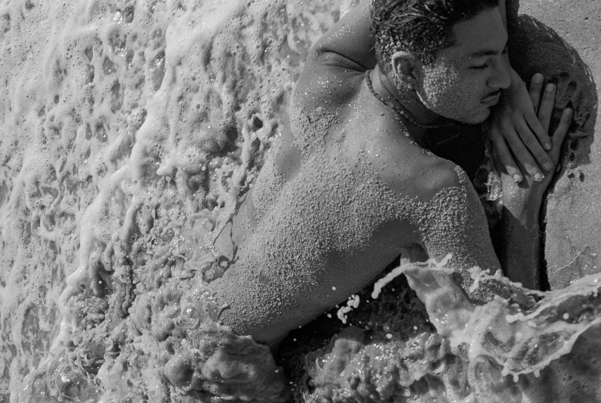 a man on a beach naked and covered in sand