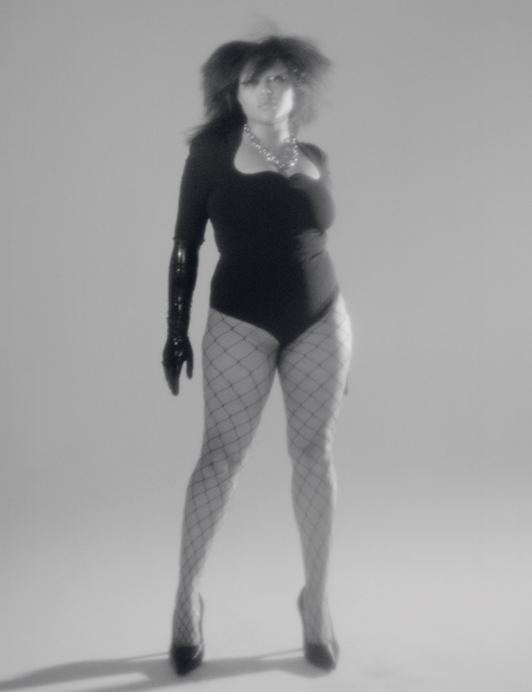 model stands facing forwards in a bodysuit and fishnets