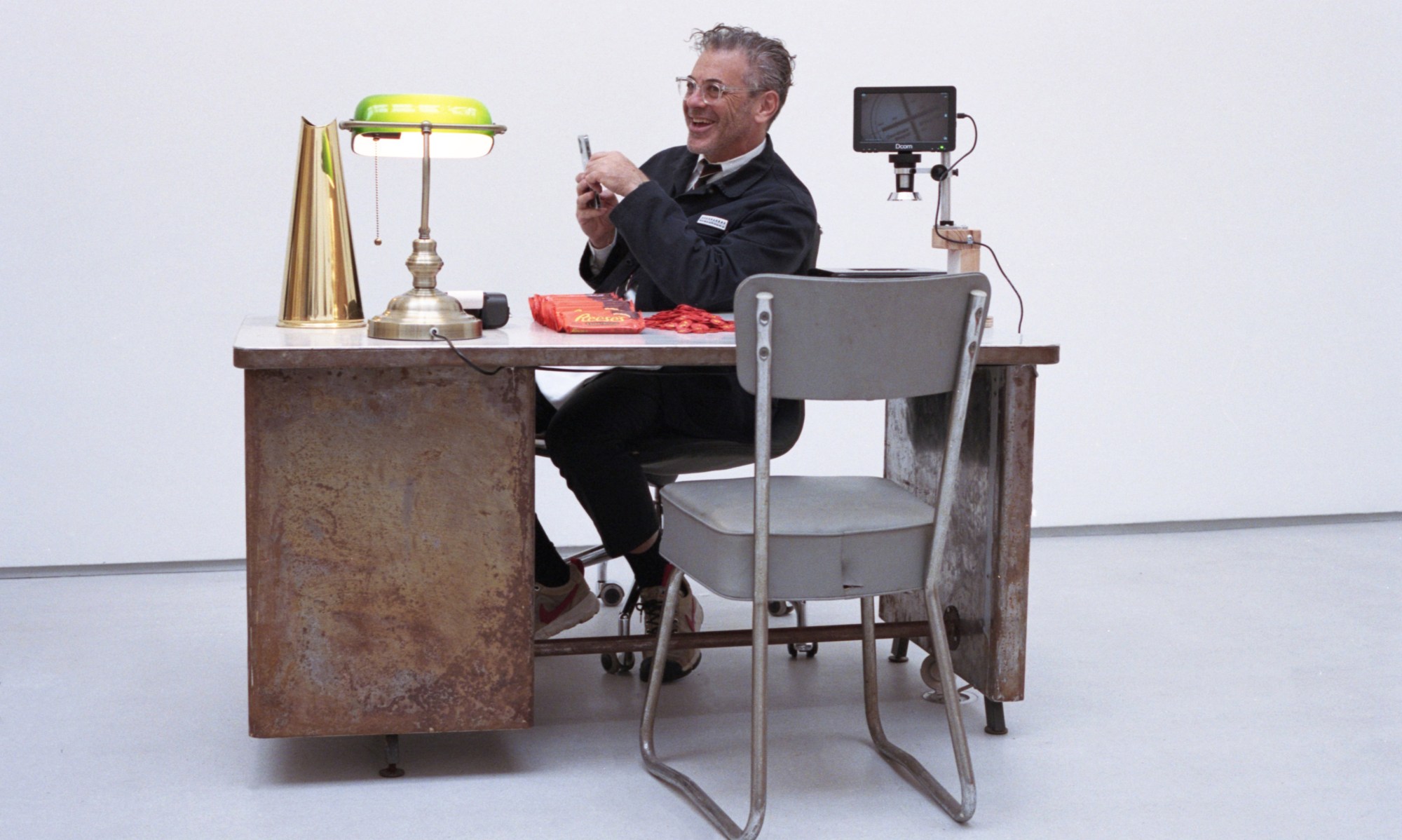 Tom Sachs sat at a desk, laughing