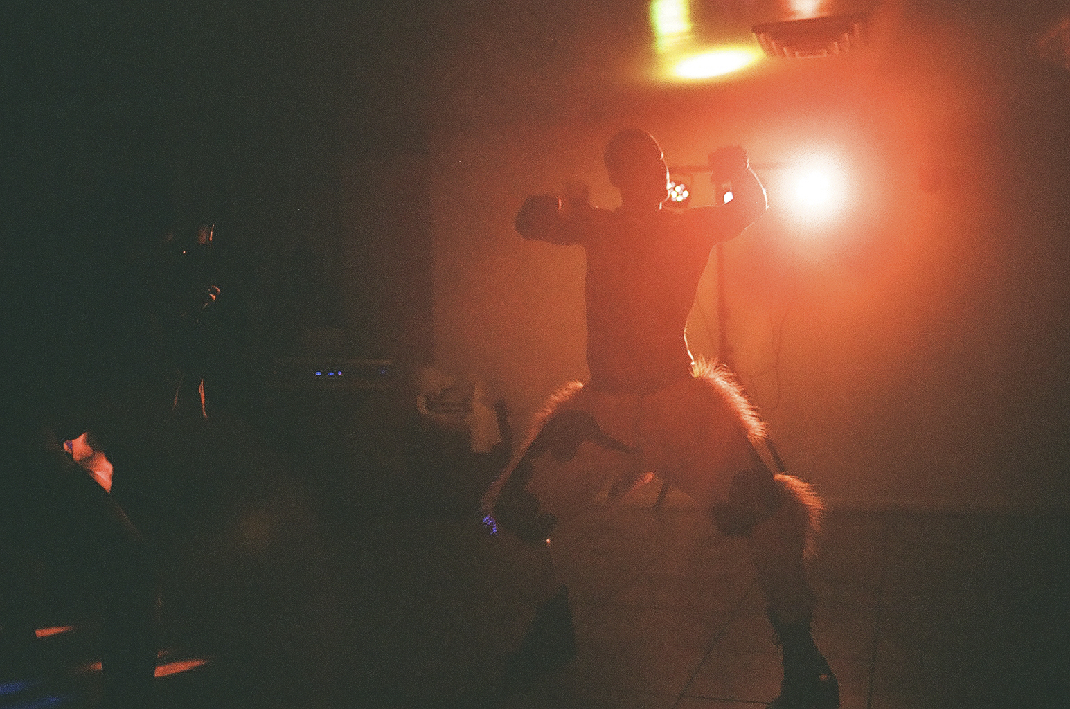 a dancing man wearing fluffy shorts is silhouetted in warm red light