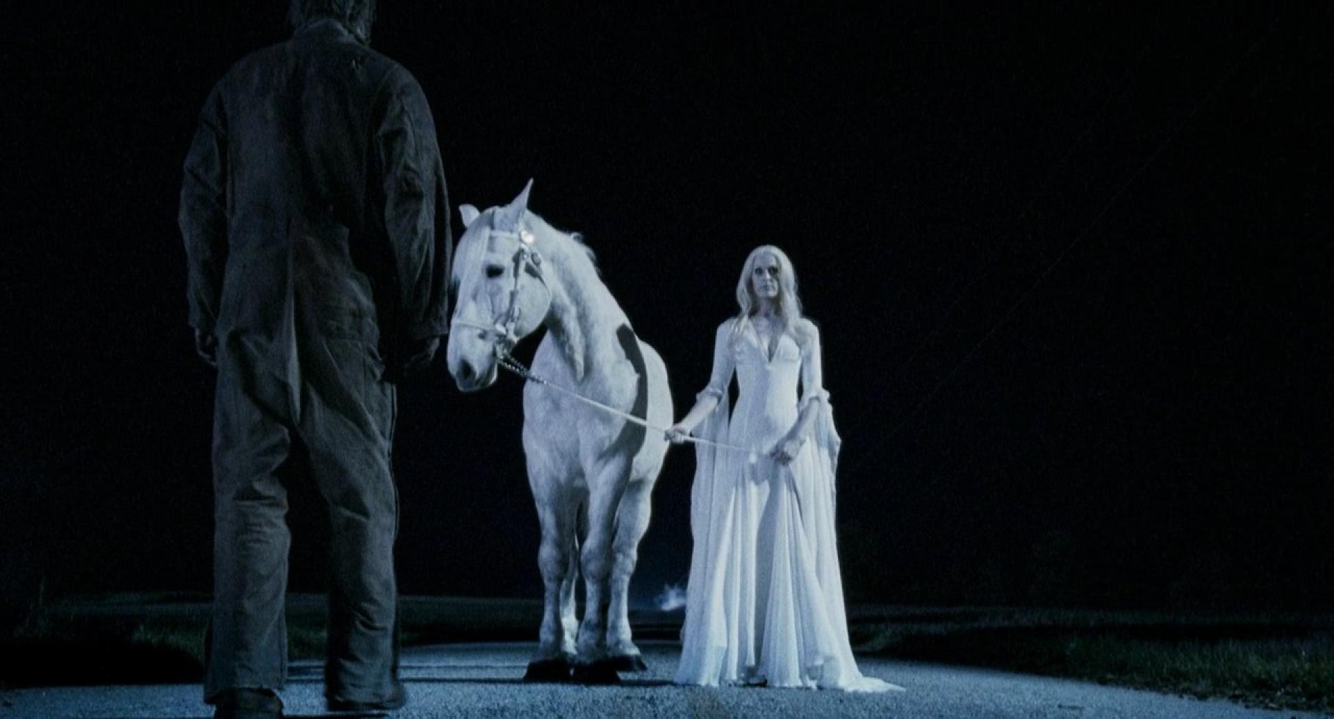 a woman dressed in white stands holding a white horse, facing a dark figure ahead