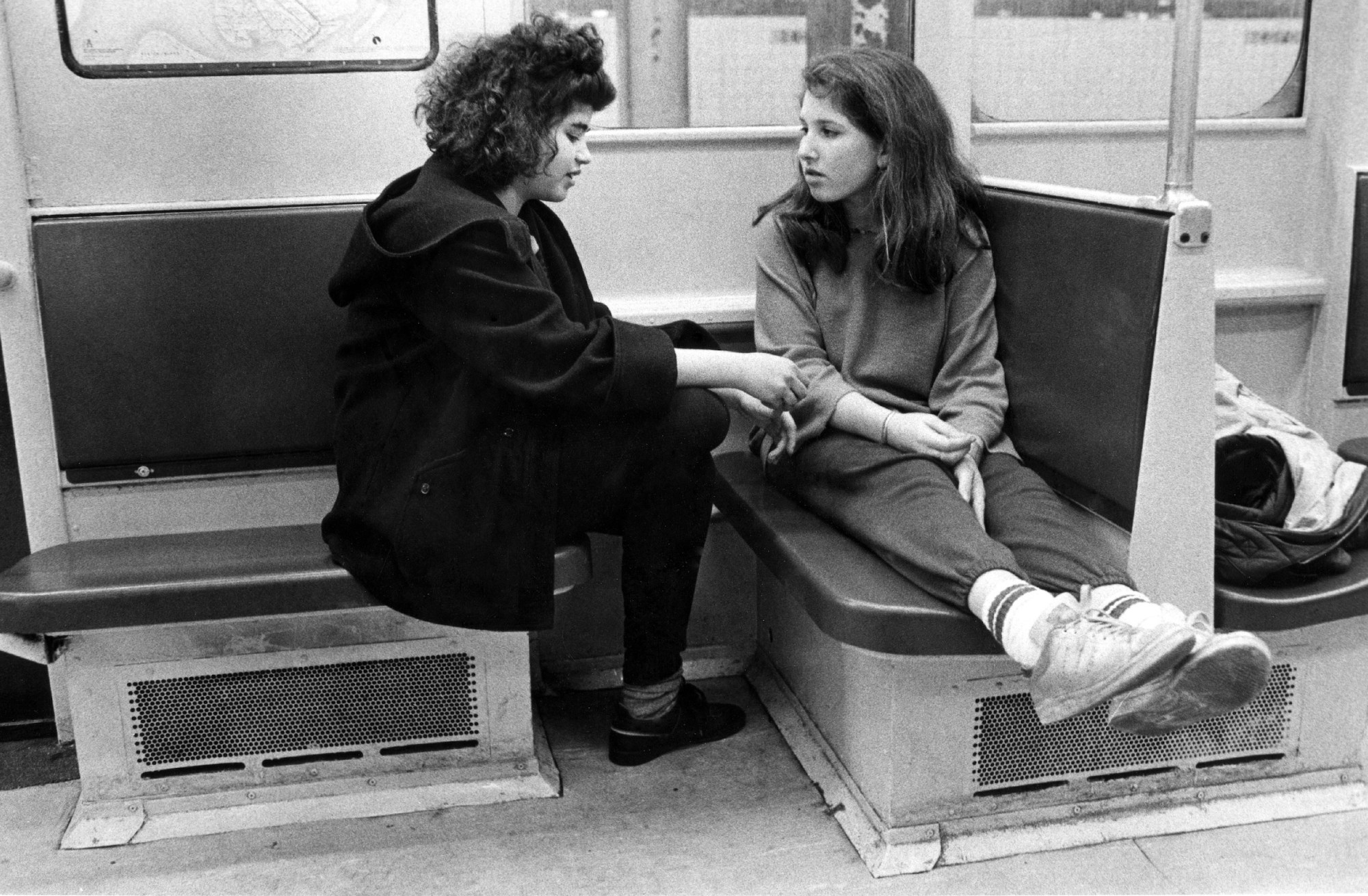 two young women sat on subway seats facing each other