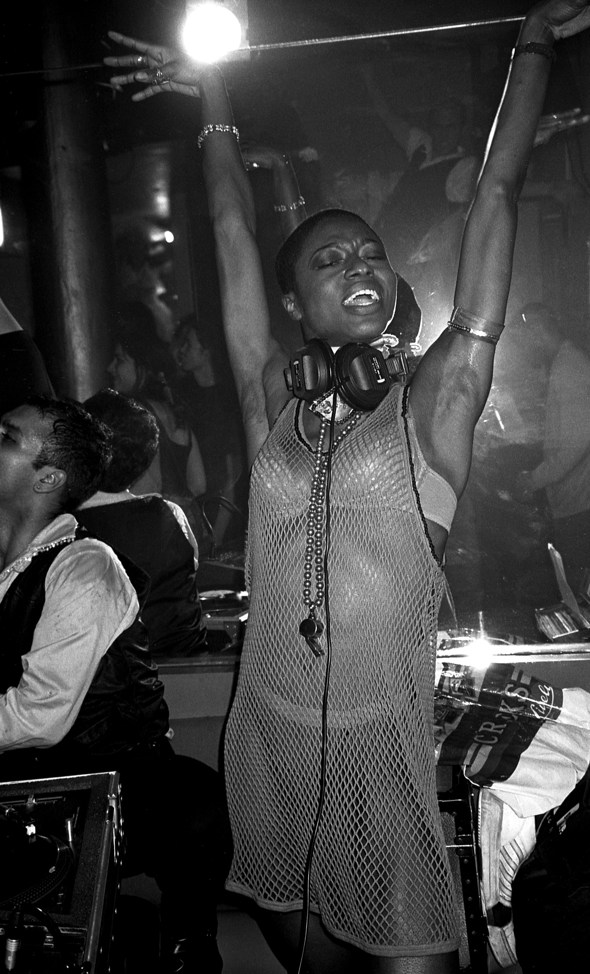 a dj in a mesh dress puts her hands in the air