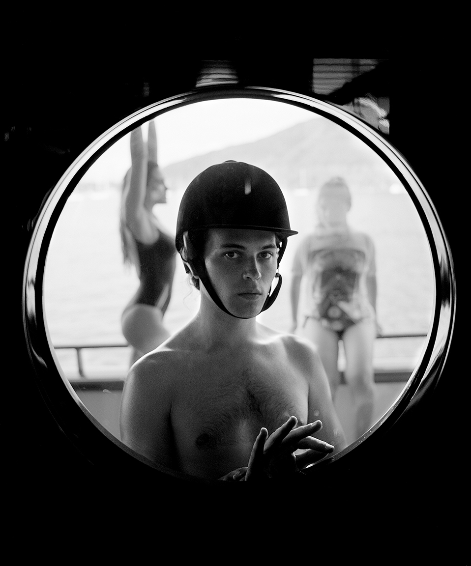 a self-portrait of michael bailey-gates looking into a circular window and wearing a helmet