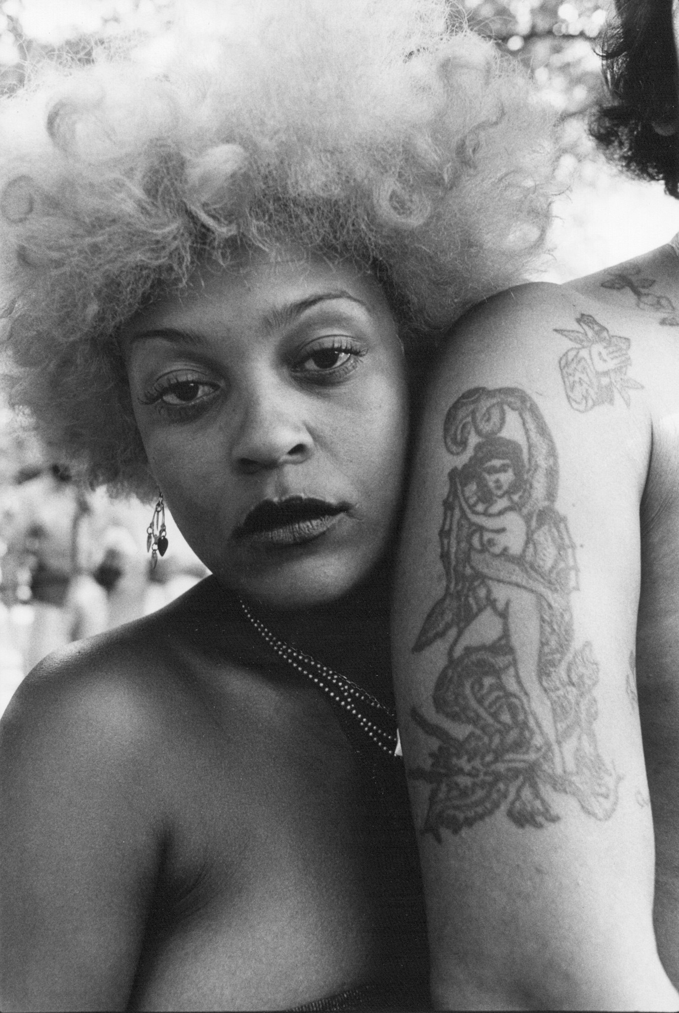 a woman leans on a tattooed arm