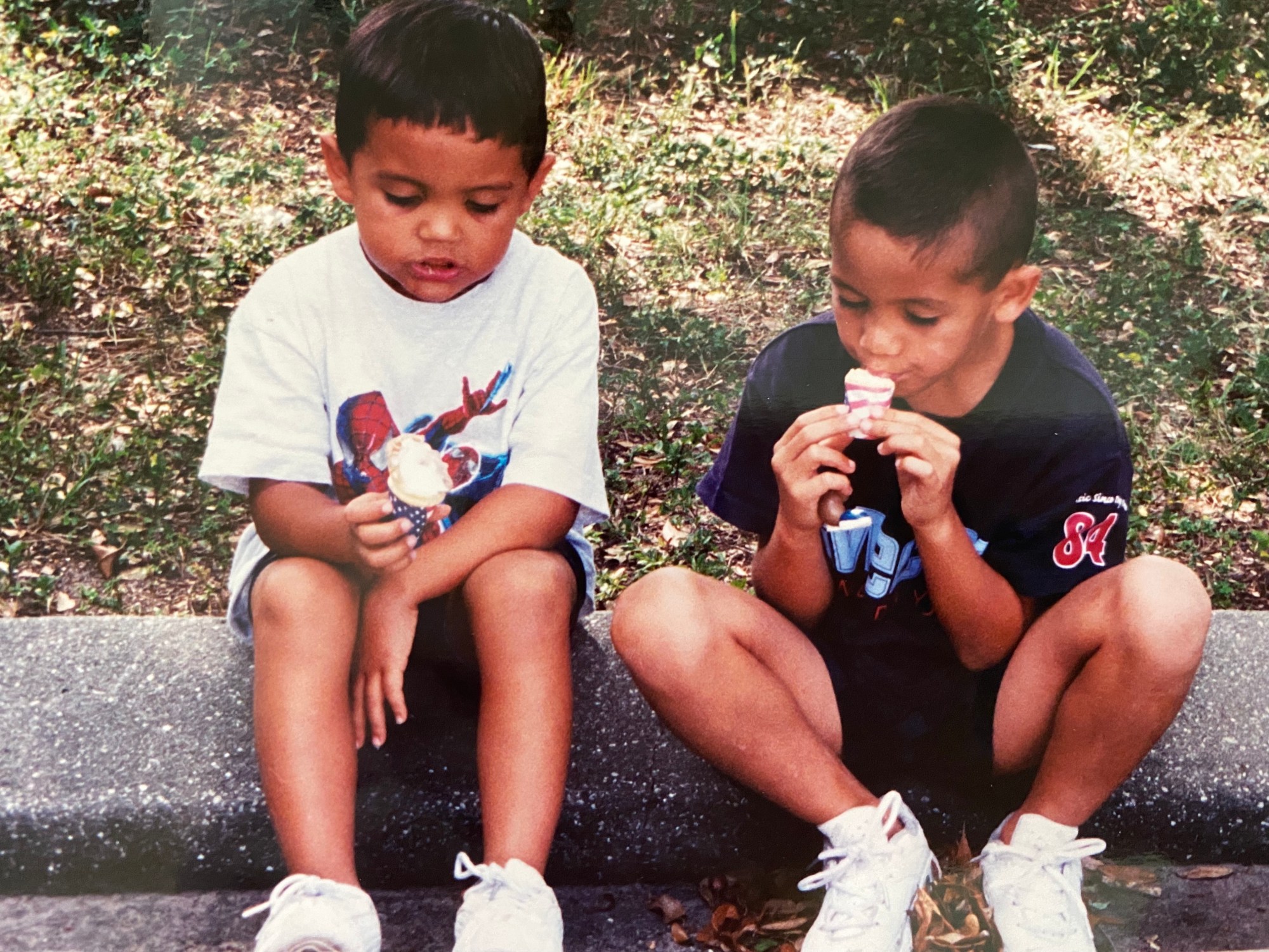 alex and dominic fike sitting on the curb and eating ice cream as kids