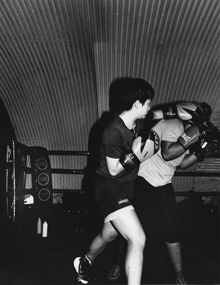 two people boxing in a ring, one hitting the other in the head