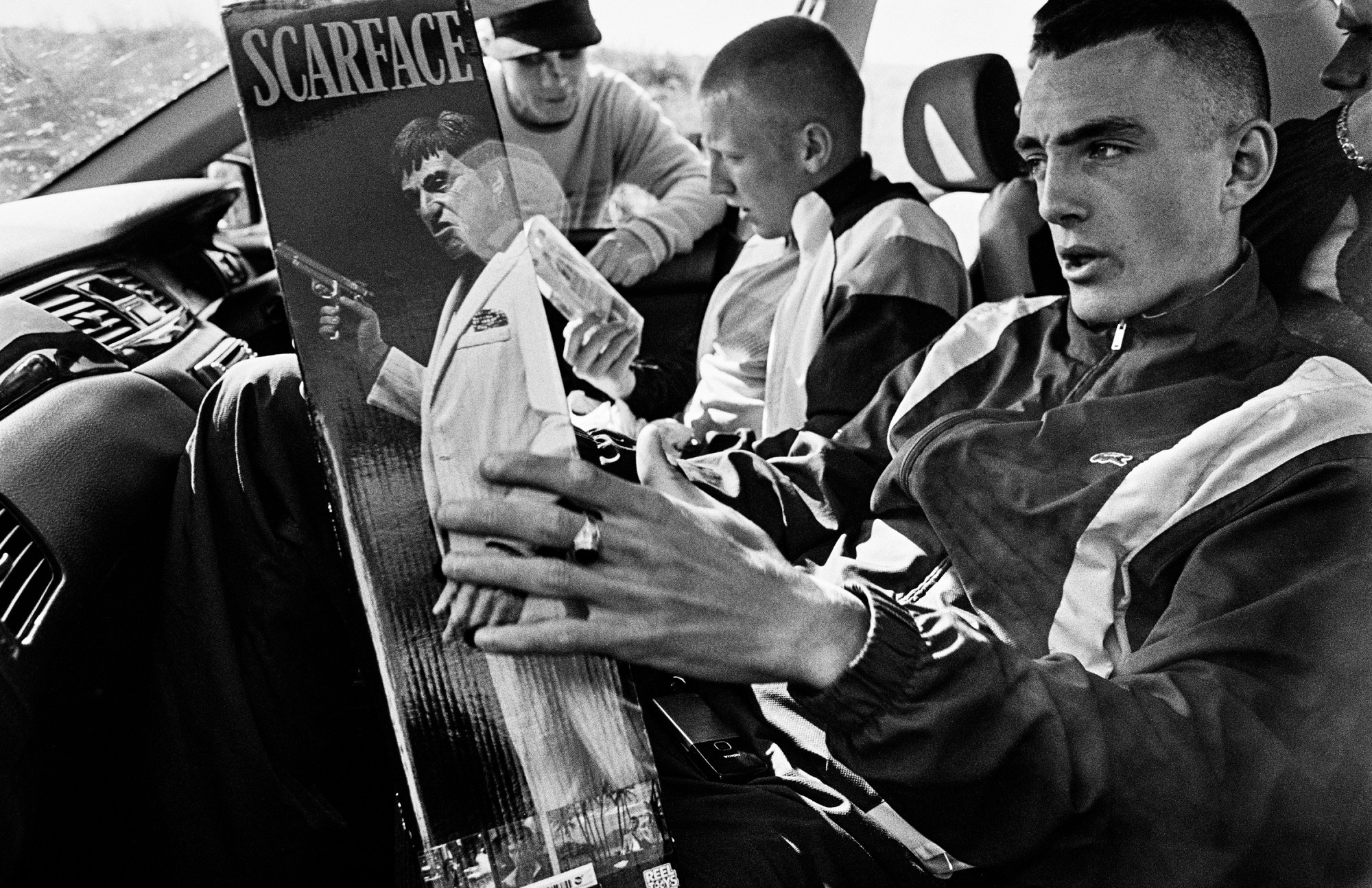 a man holds a scarface poster in a car