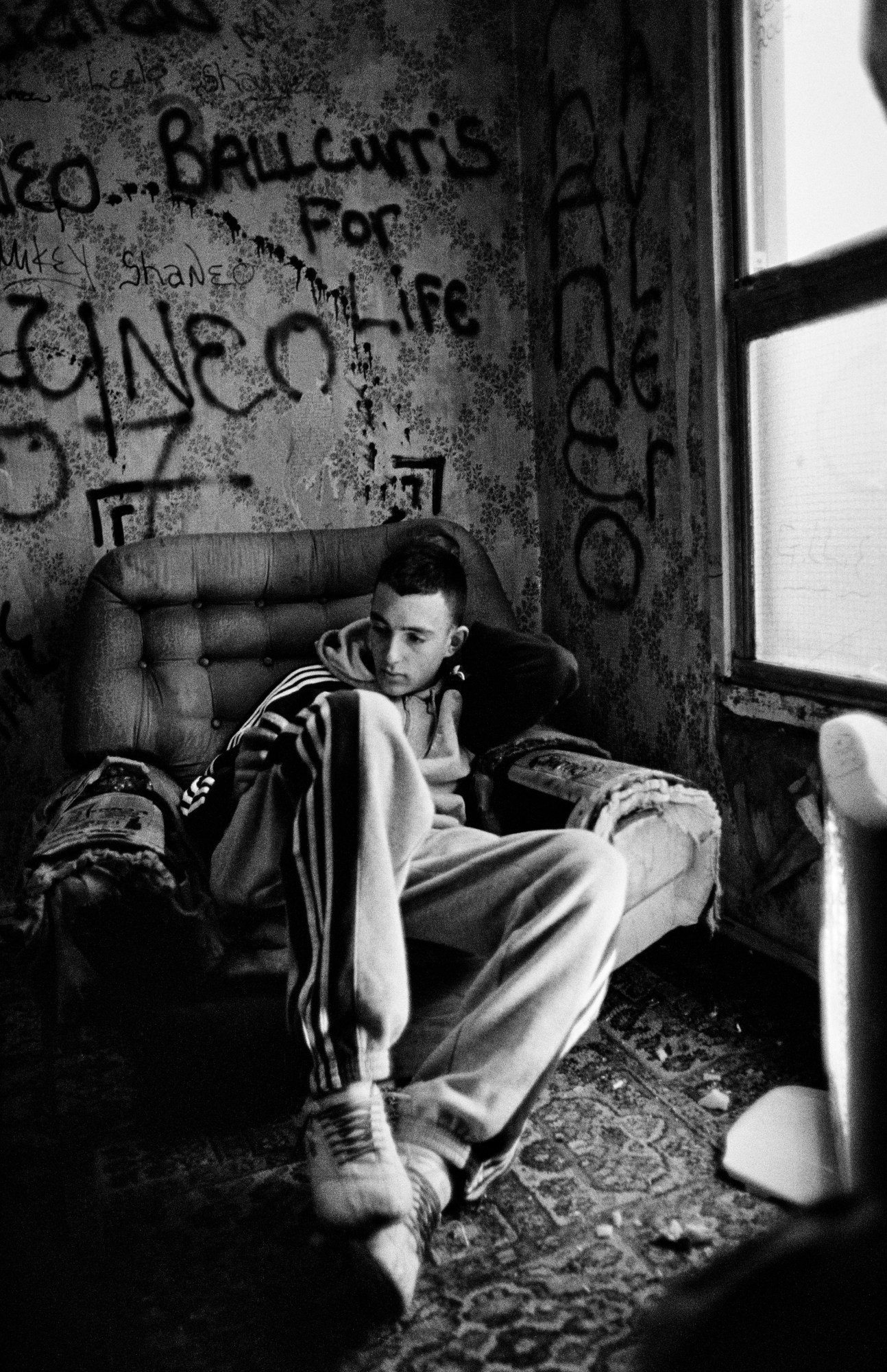 a young man sits in a graffiti covered room