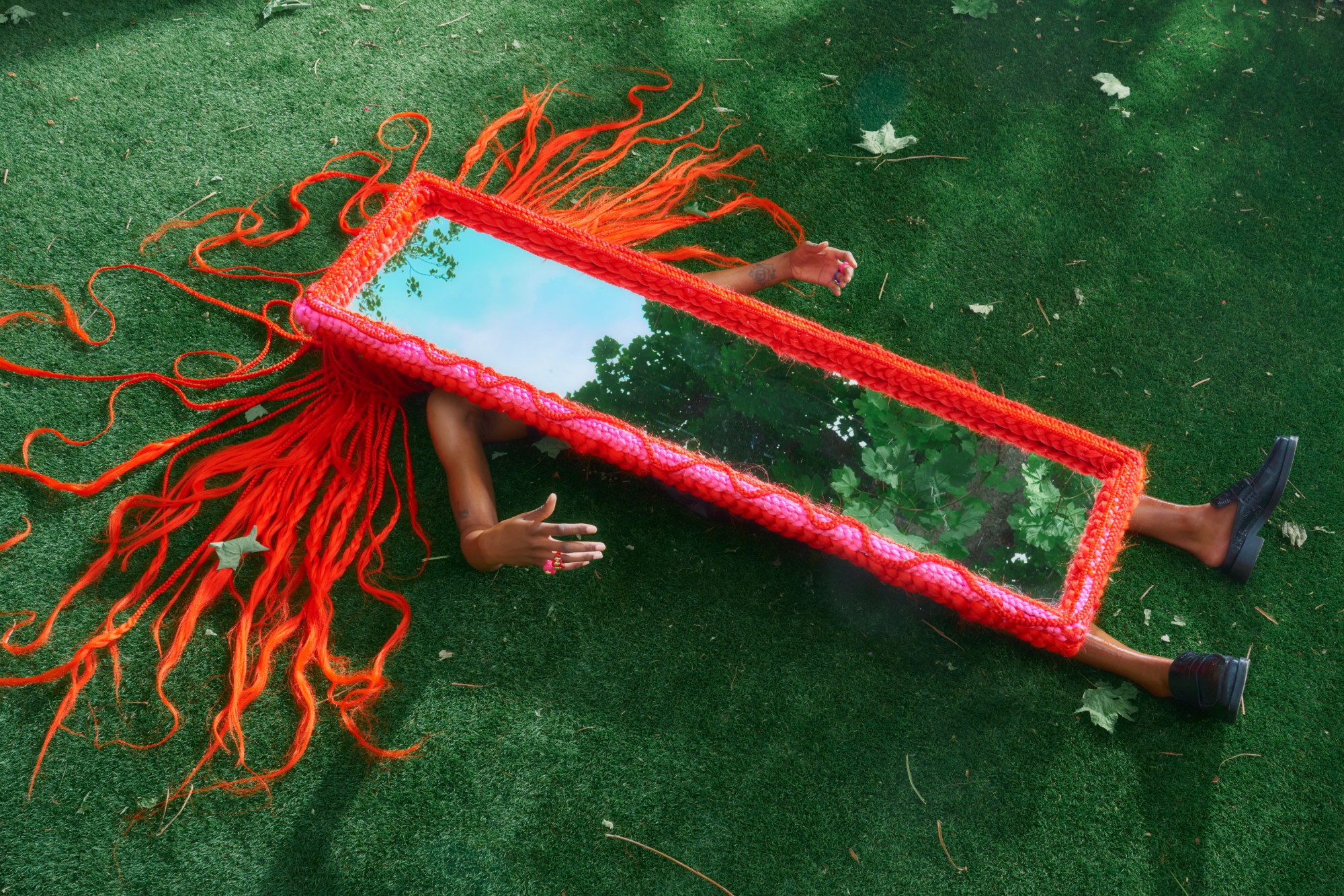 Mirror wrapped in braided orange hair extensions lying on the floor