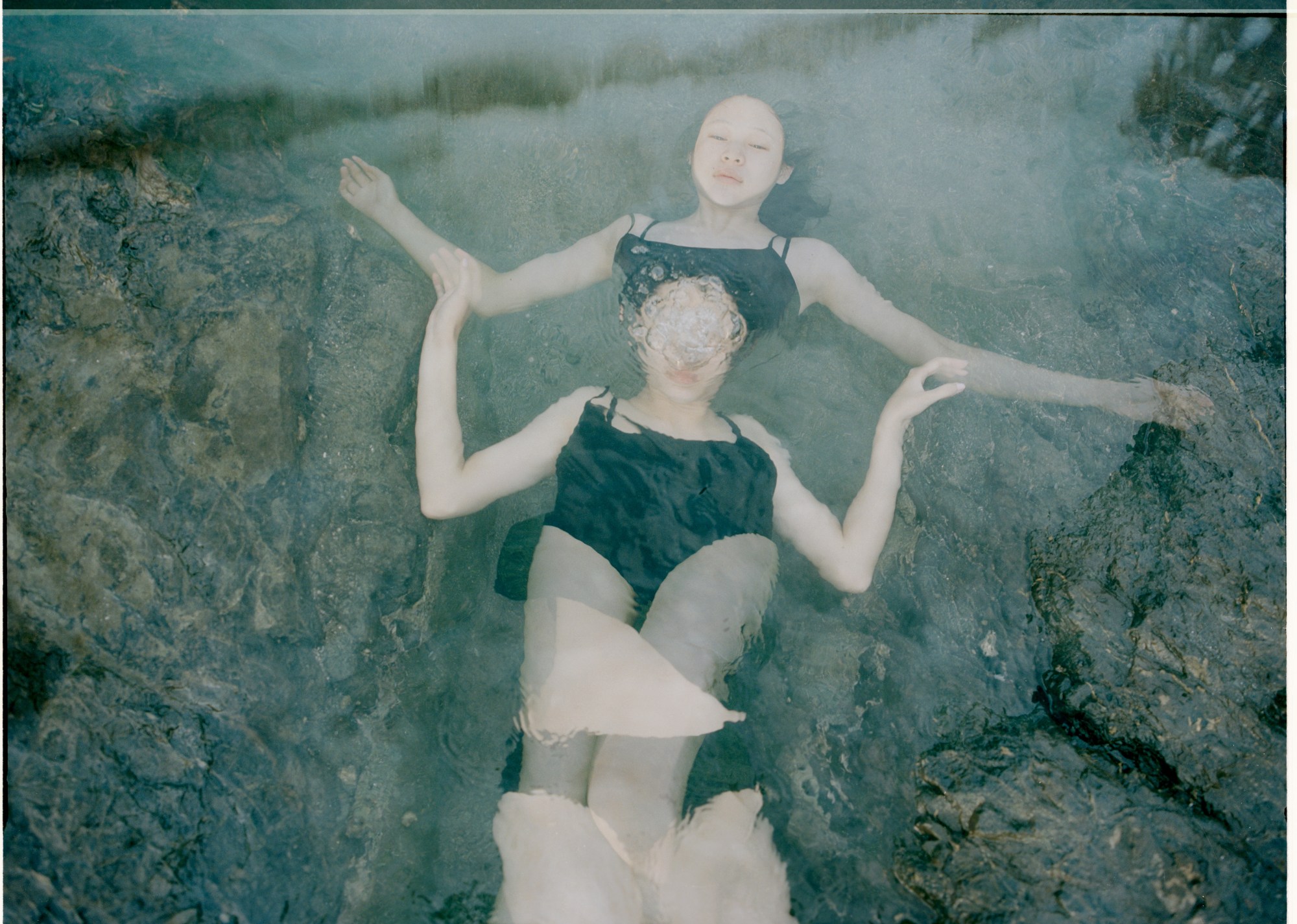 a double exposed photo of a woman laying on her back, floating in the sea