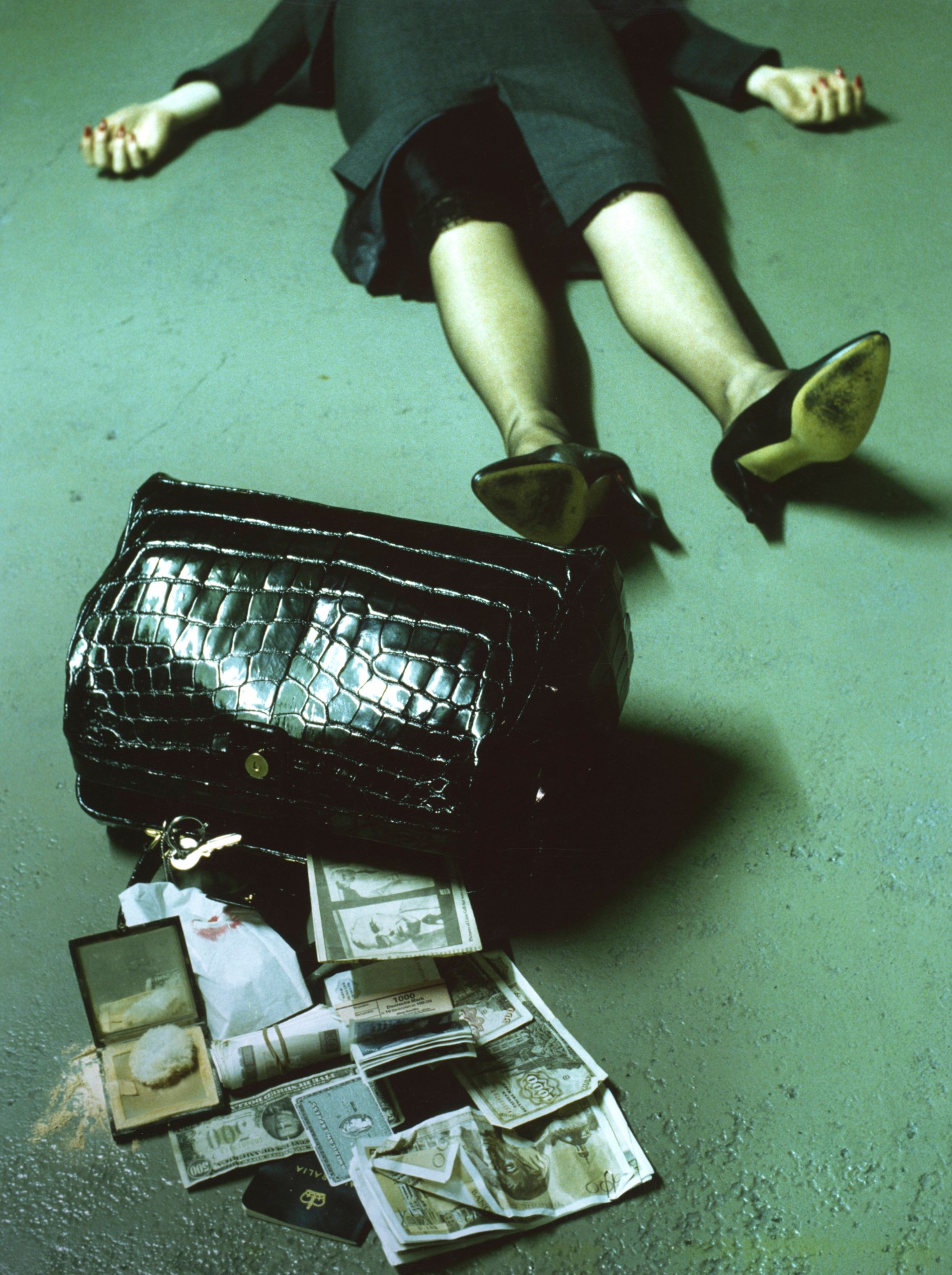 a woman lying on the floor, her face out of shot, and money pouring and credit cards falling out of a bag