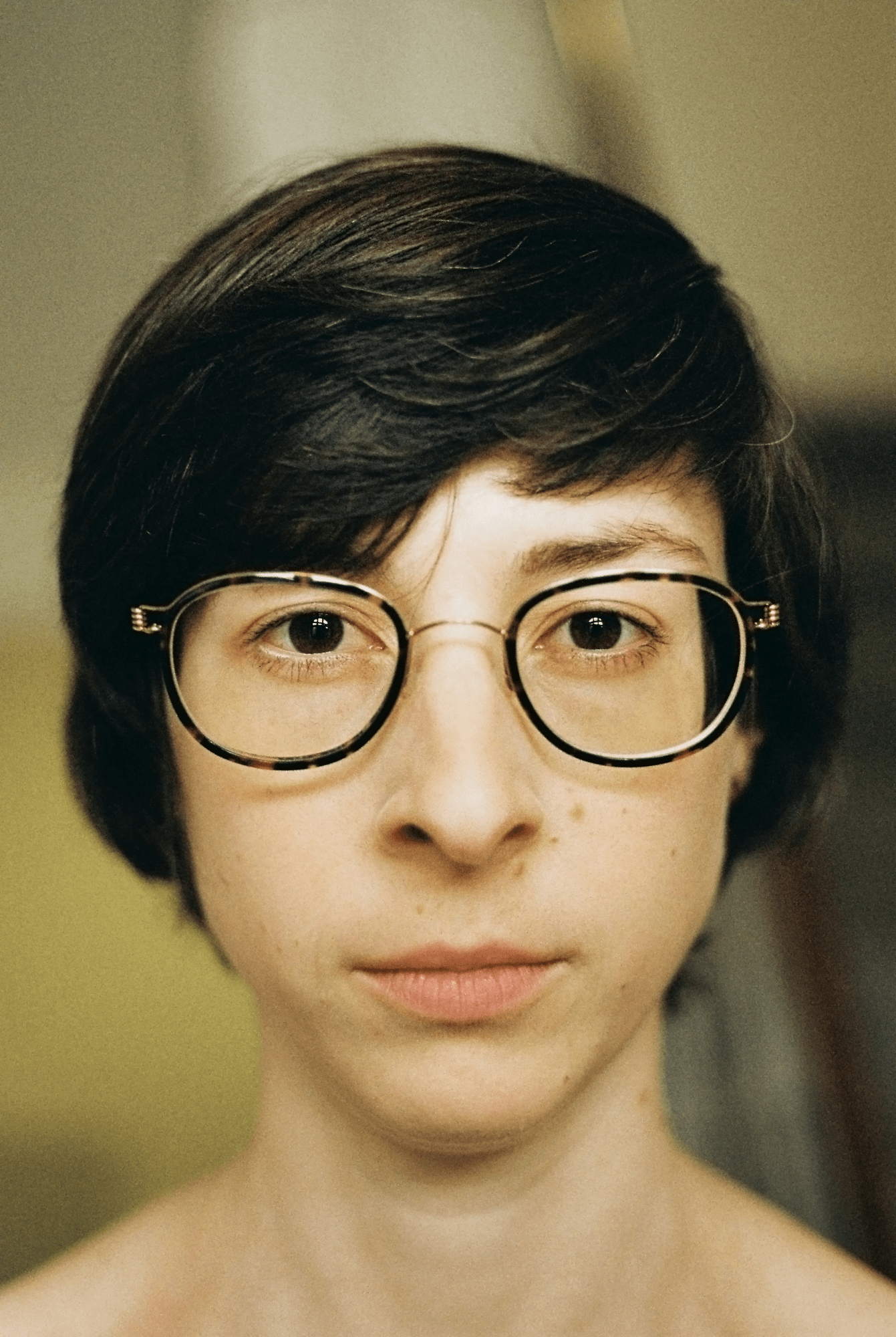 a person with glasses, looks directly into the camera lens