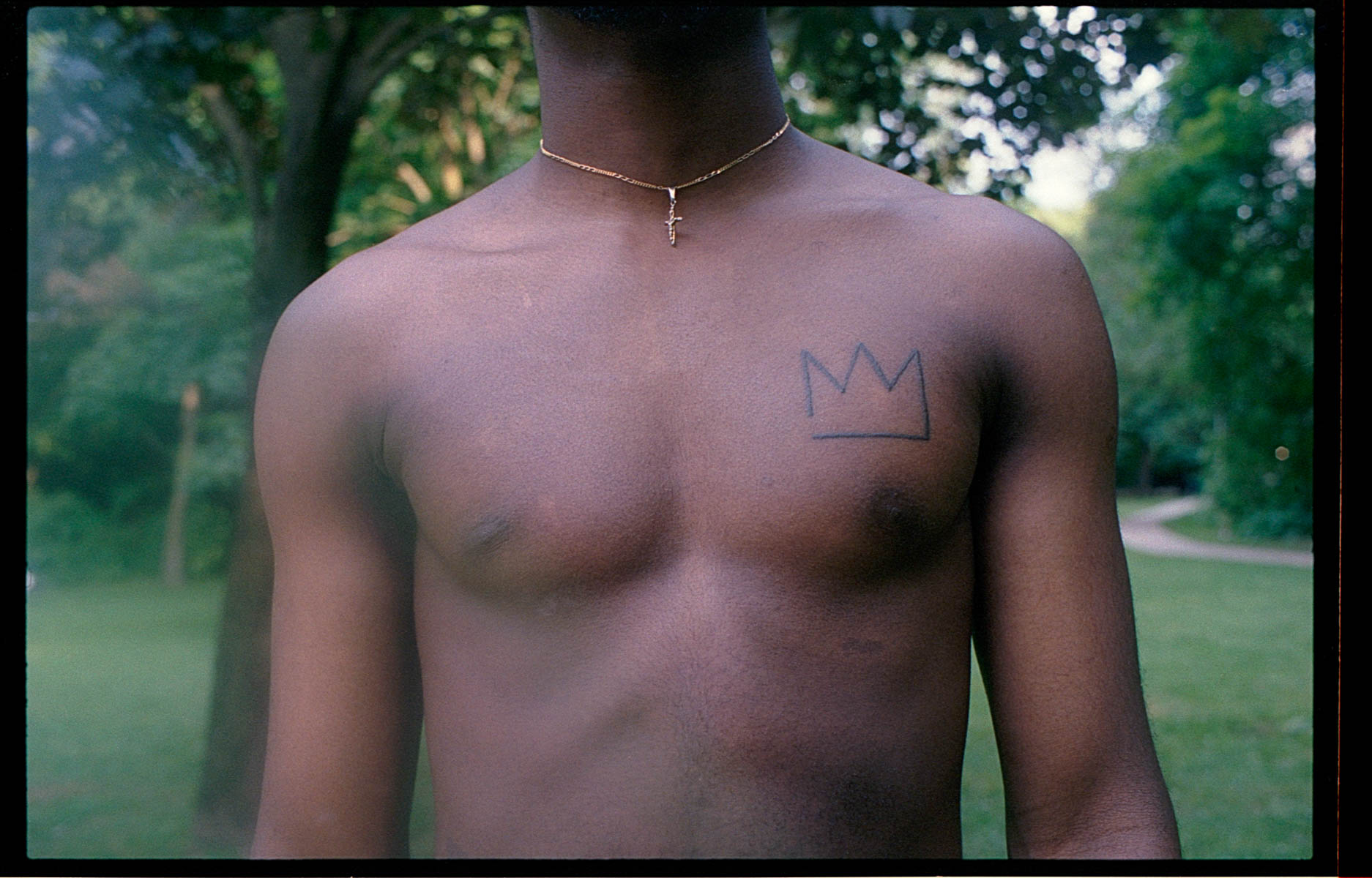 the chest of a topless man with a crown heart on his left side