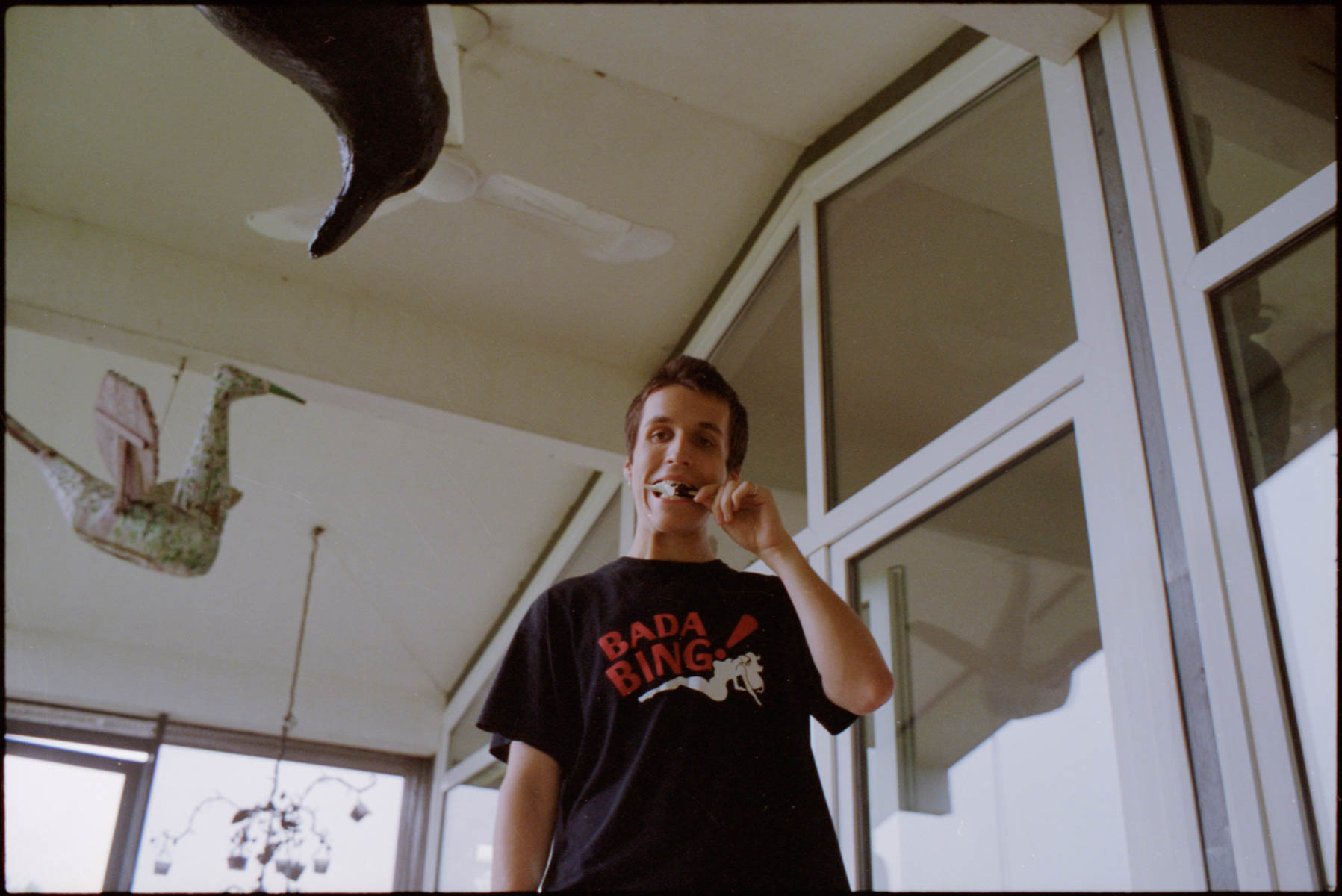 a young man in a t-shirt that reads 'bada bing' brushes his teeth