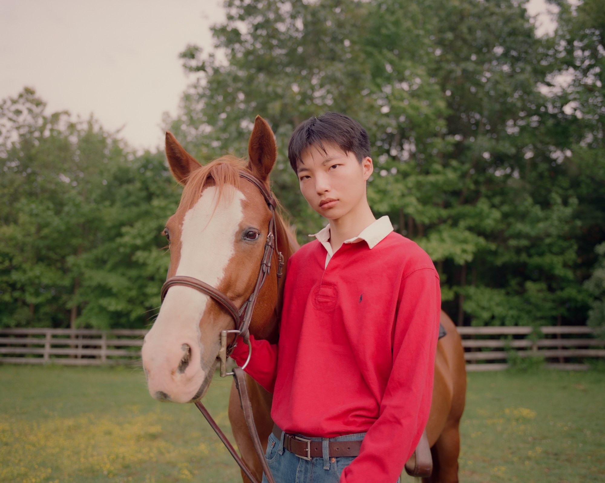 model wears Ralph Lauren as they stand next to a horse in a green field.