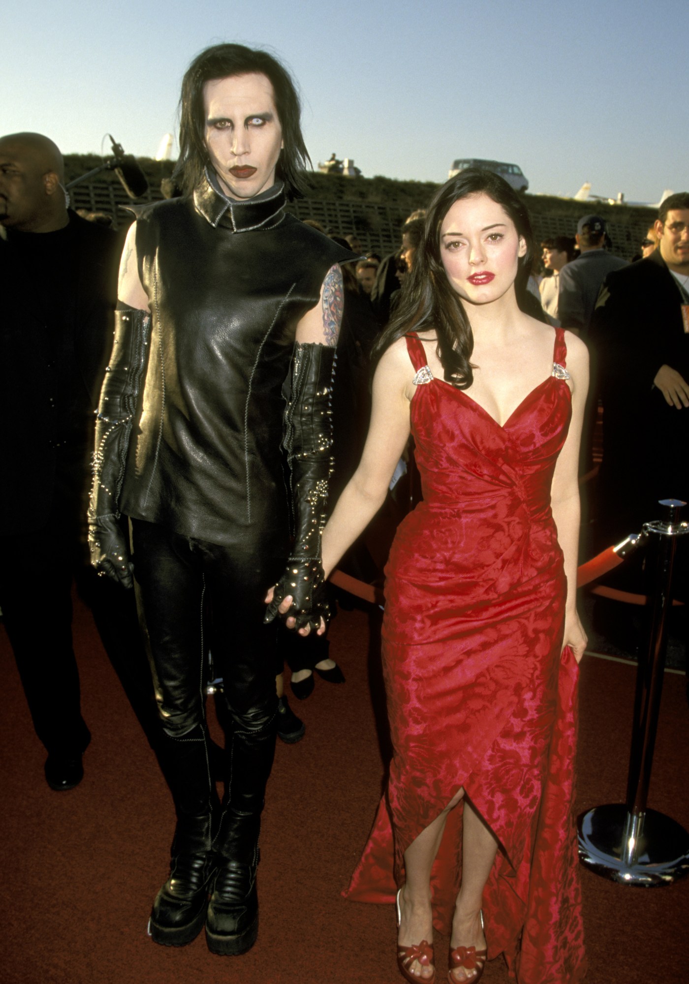 rose mcgowan wearing a red dress and holding hands with marilyn manson mtv movie awards 1999