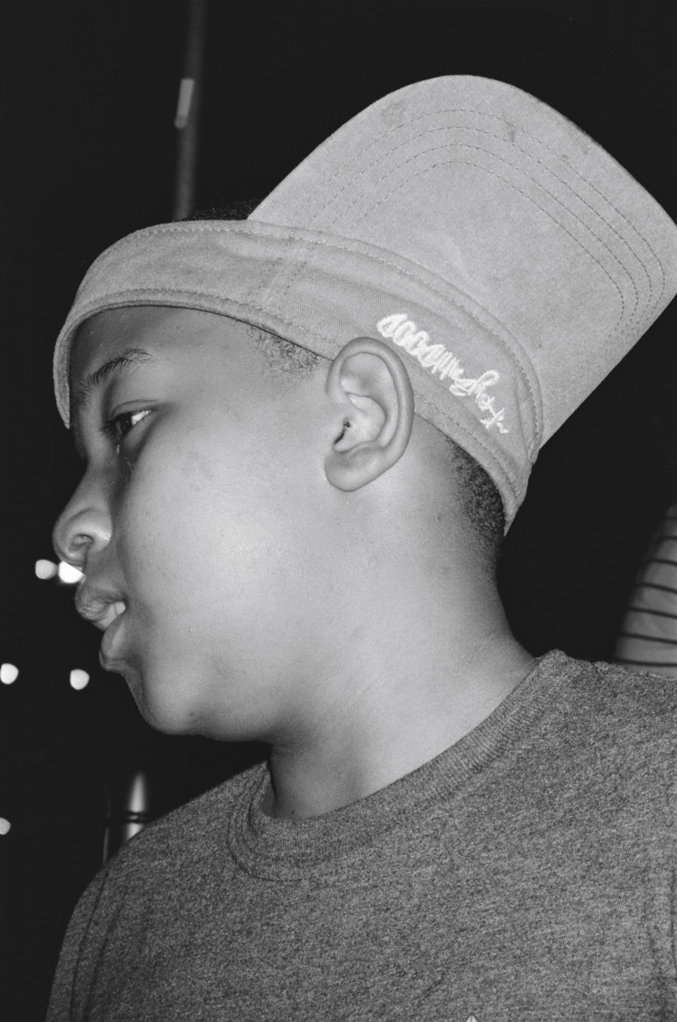 A young boy’s side profile, wearing a cap upside down and back to front