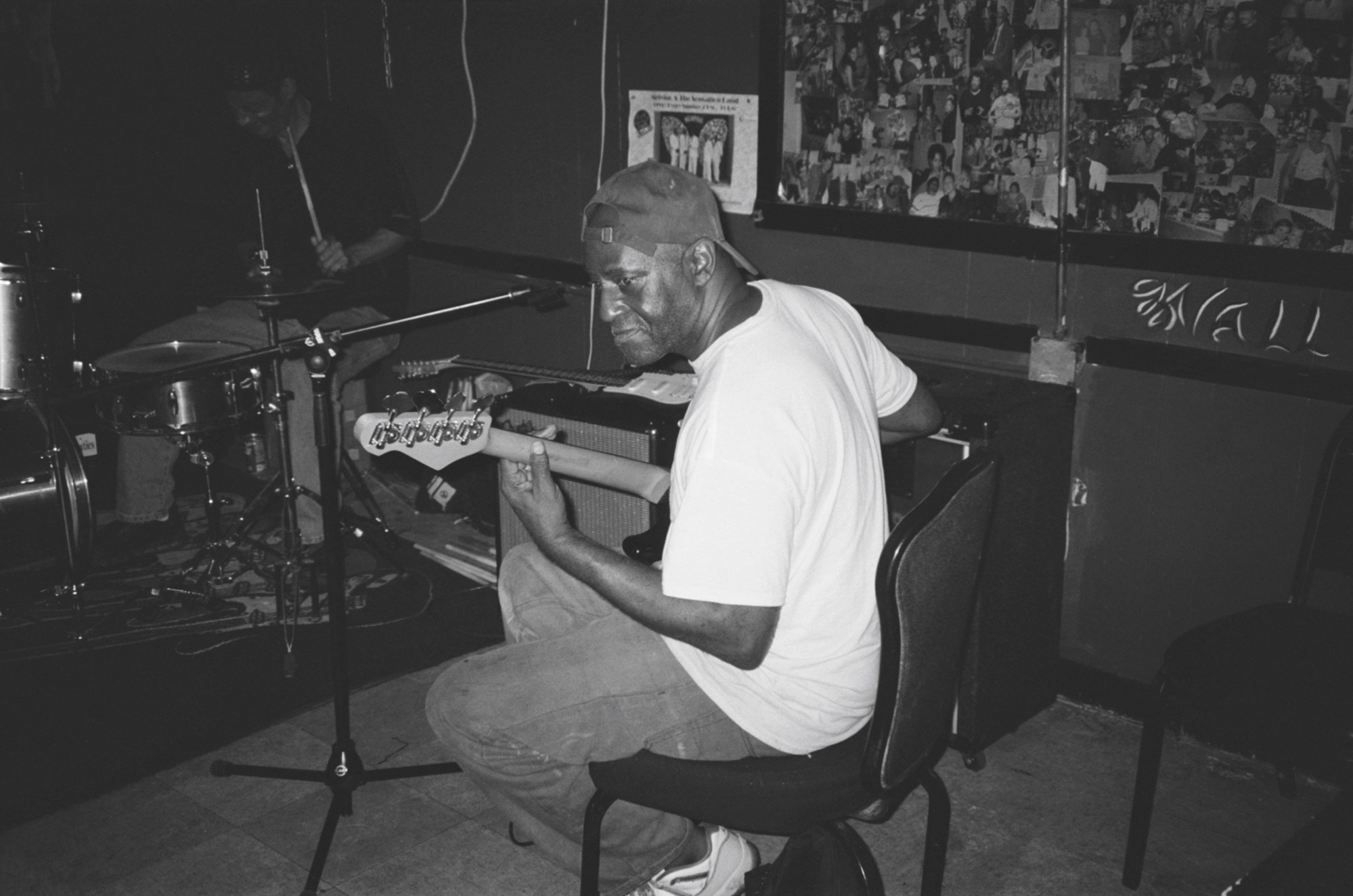 A side portrait of a man wearing a backwards cap while playing a guitar