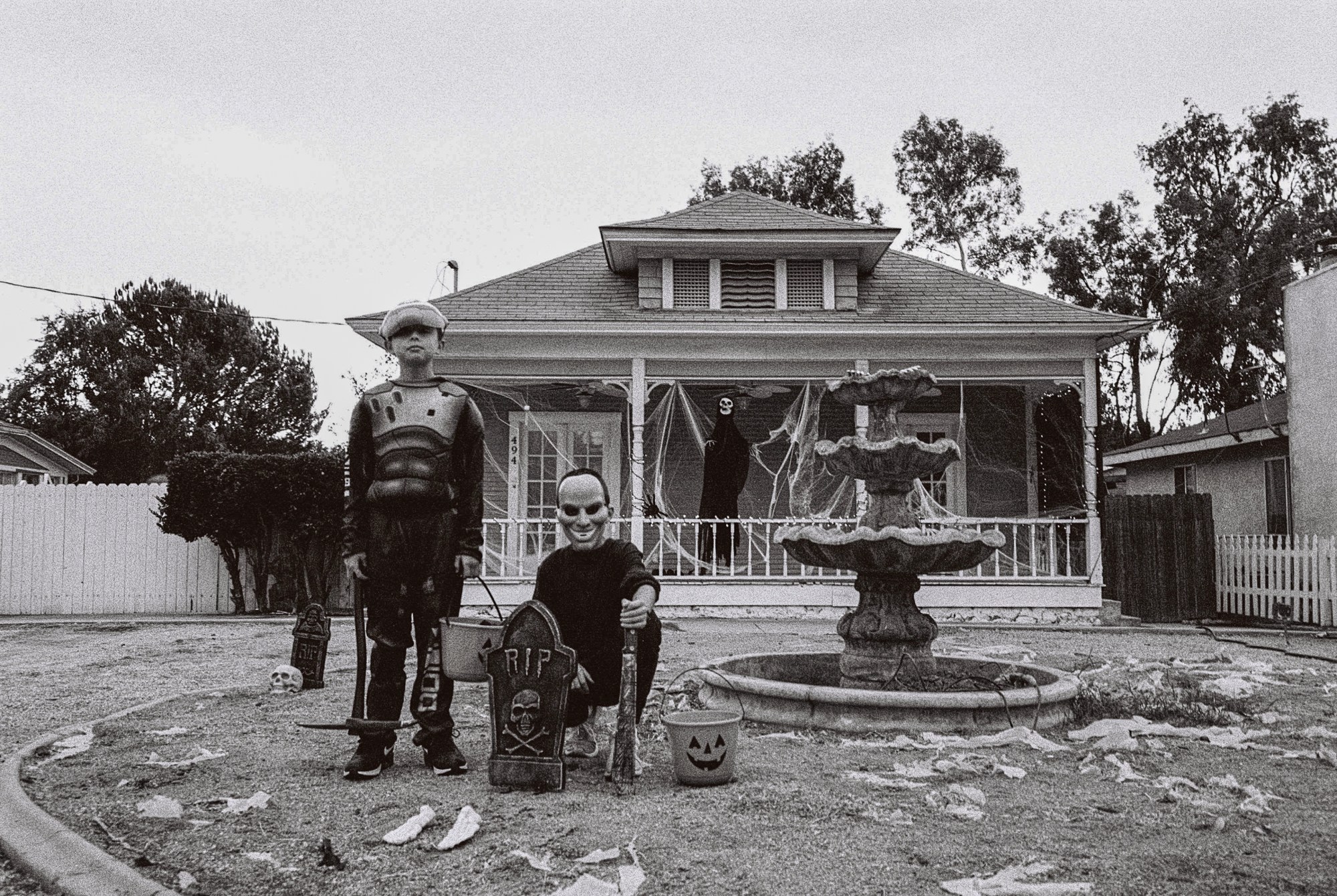 kids in halloween costumes outside a spookily decorated house