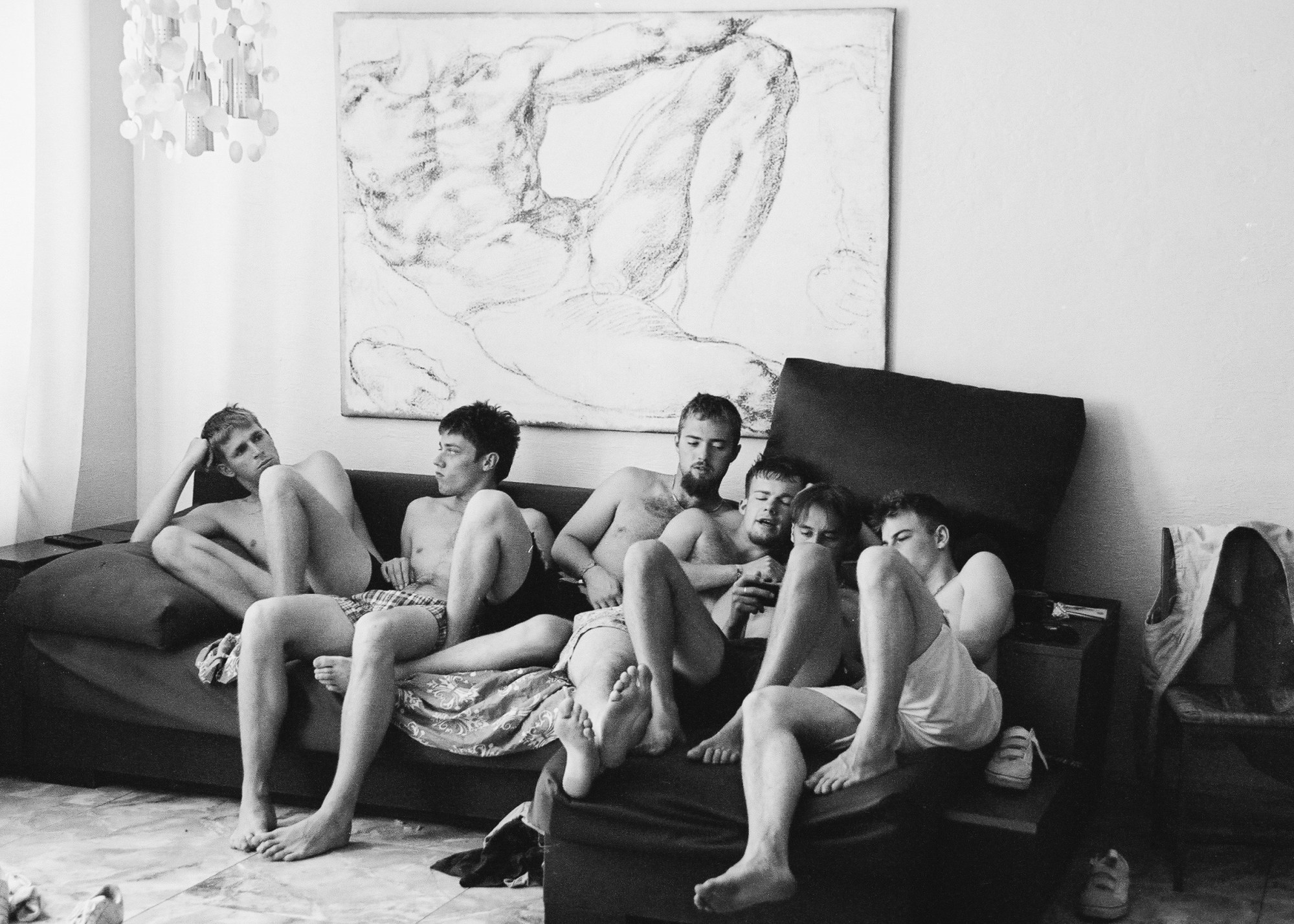 six boys in shorts sit on a sofa in front of Michelangelo's painting