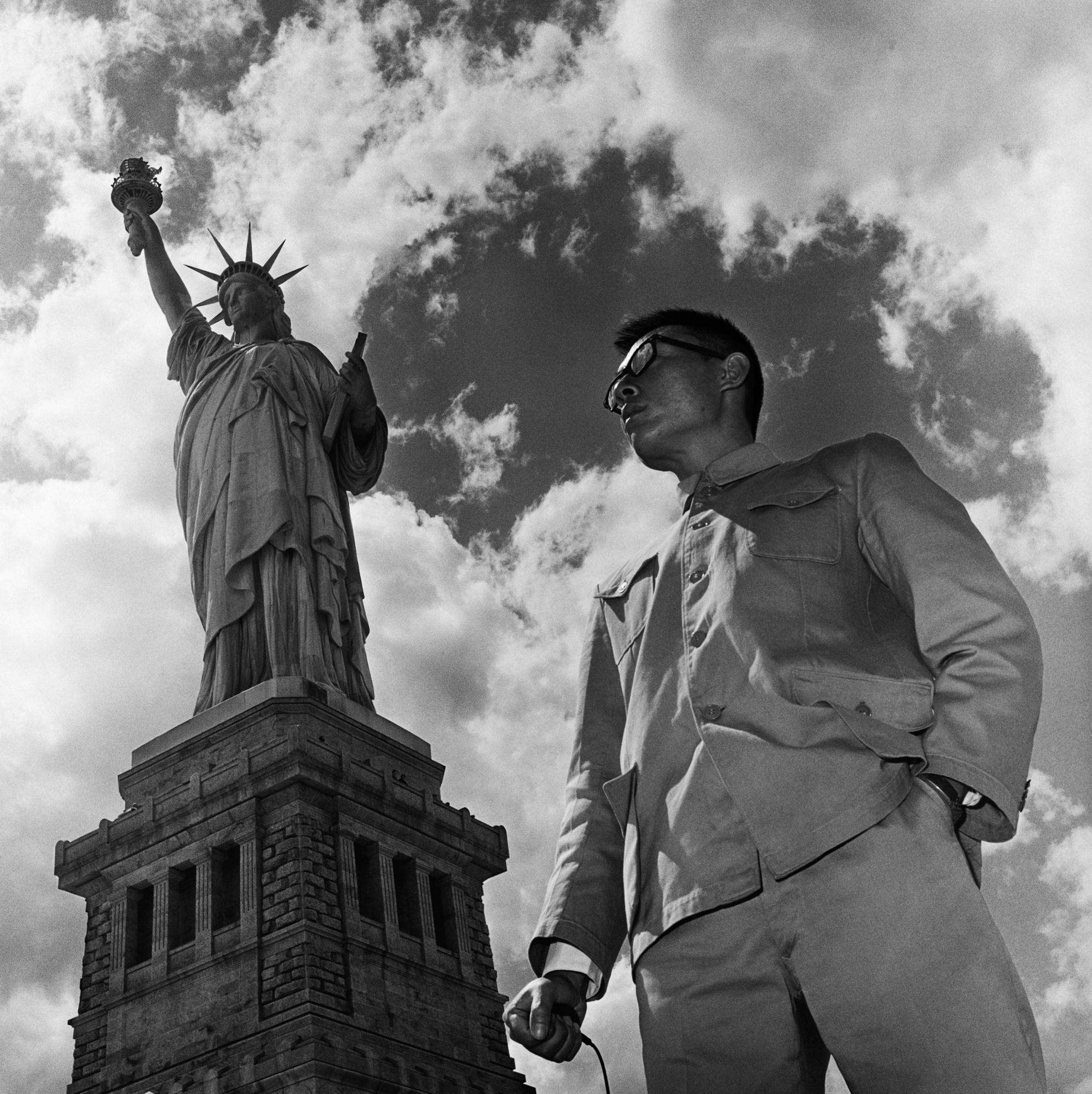 a man in a Zhongshan suit stood in front of the statue of liberty