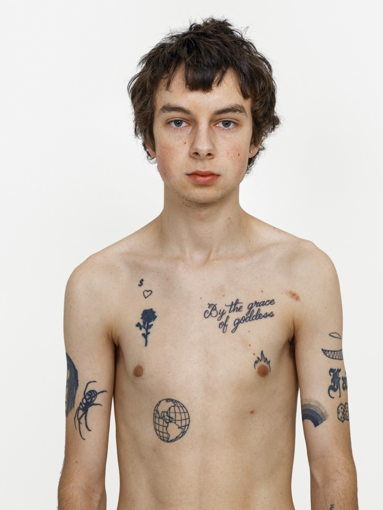 A young topless man with tattoos on his torso and arms