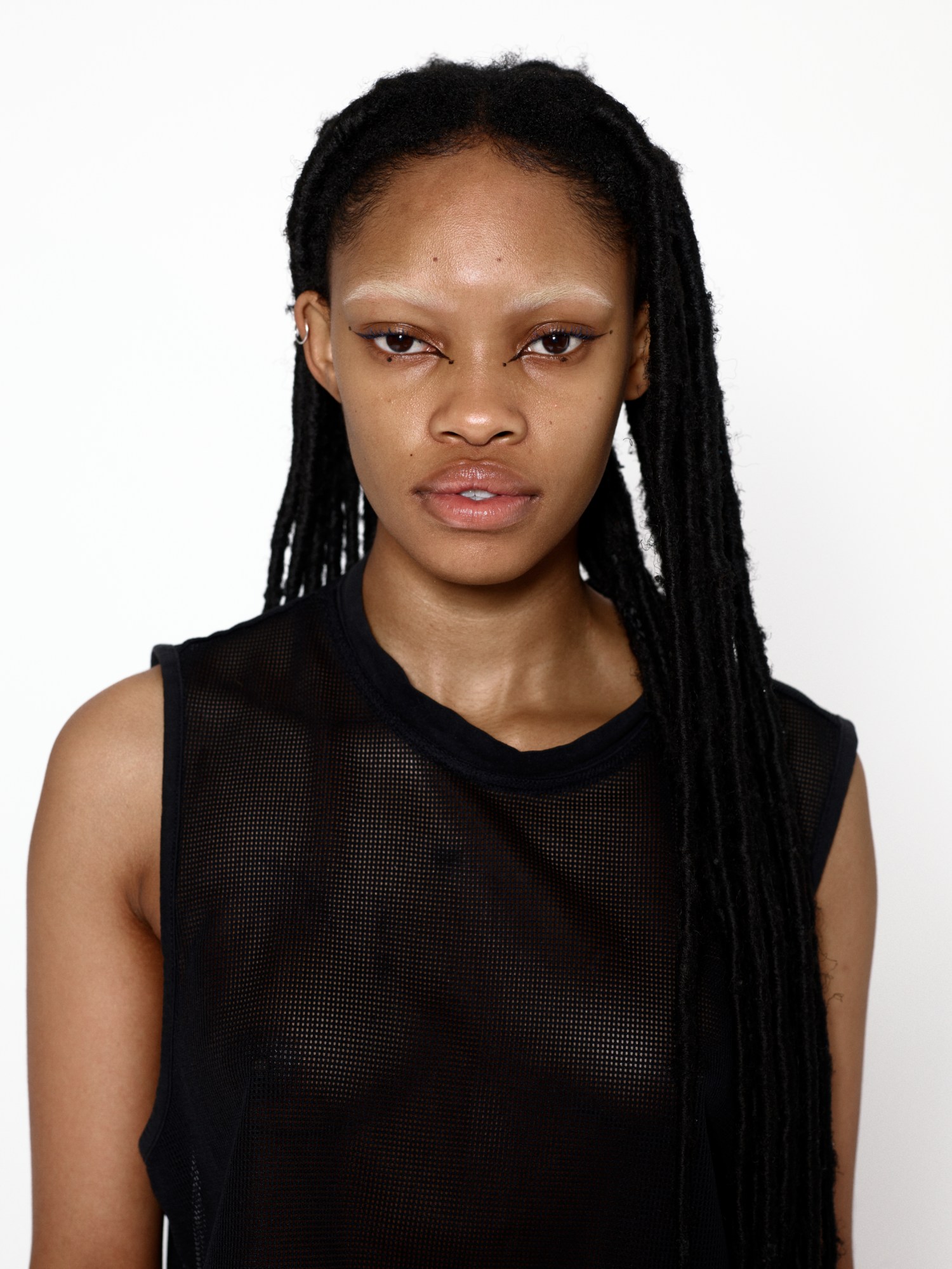 A woman with long black dreads wearing a mesh vest top