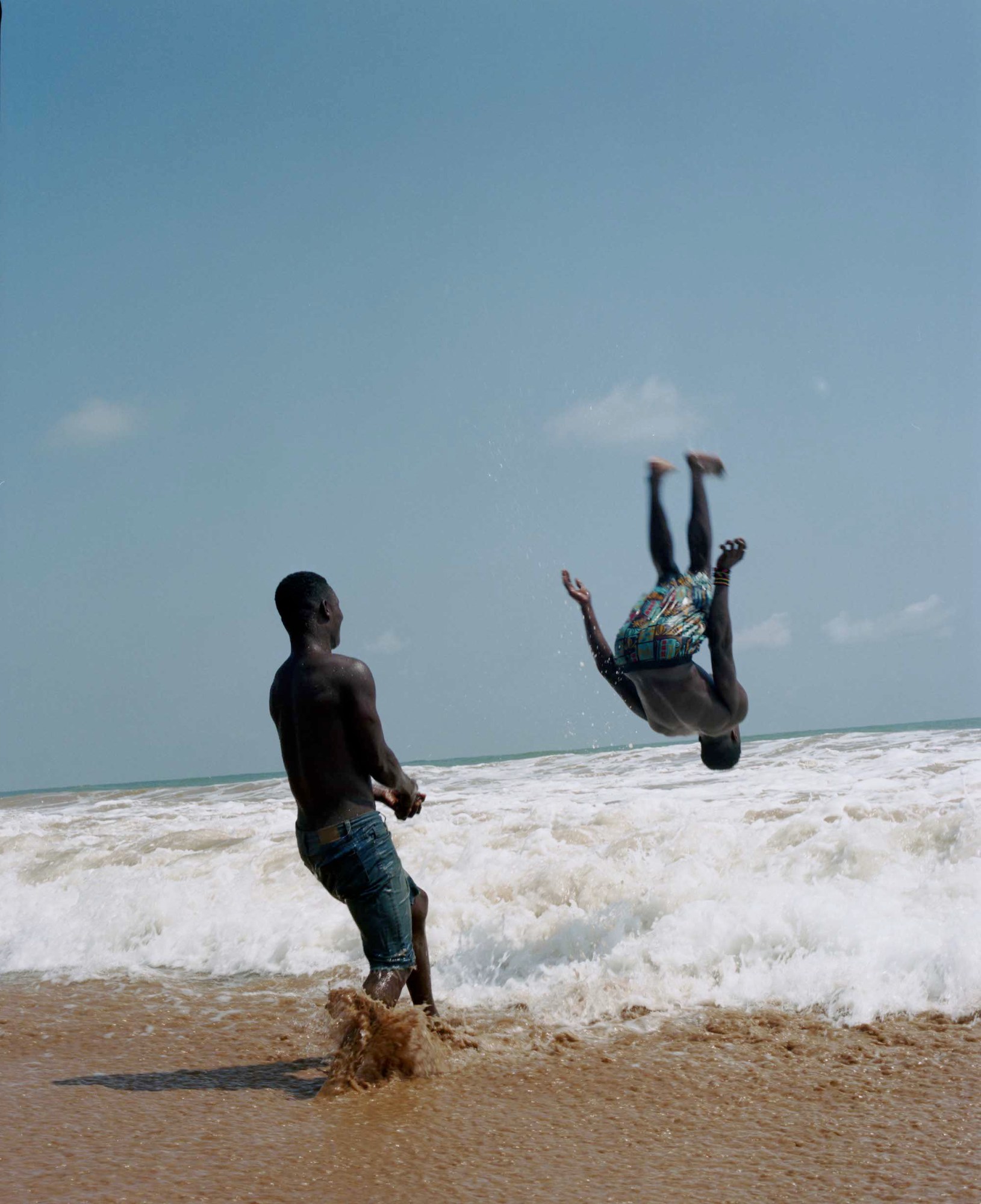 two boys doing backflips in the ocean in ghana