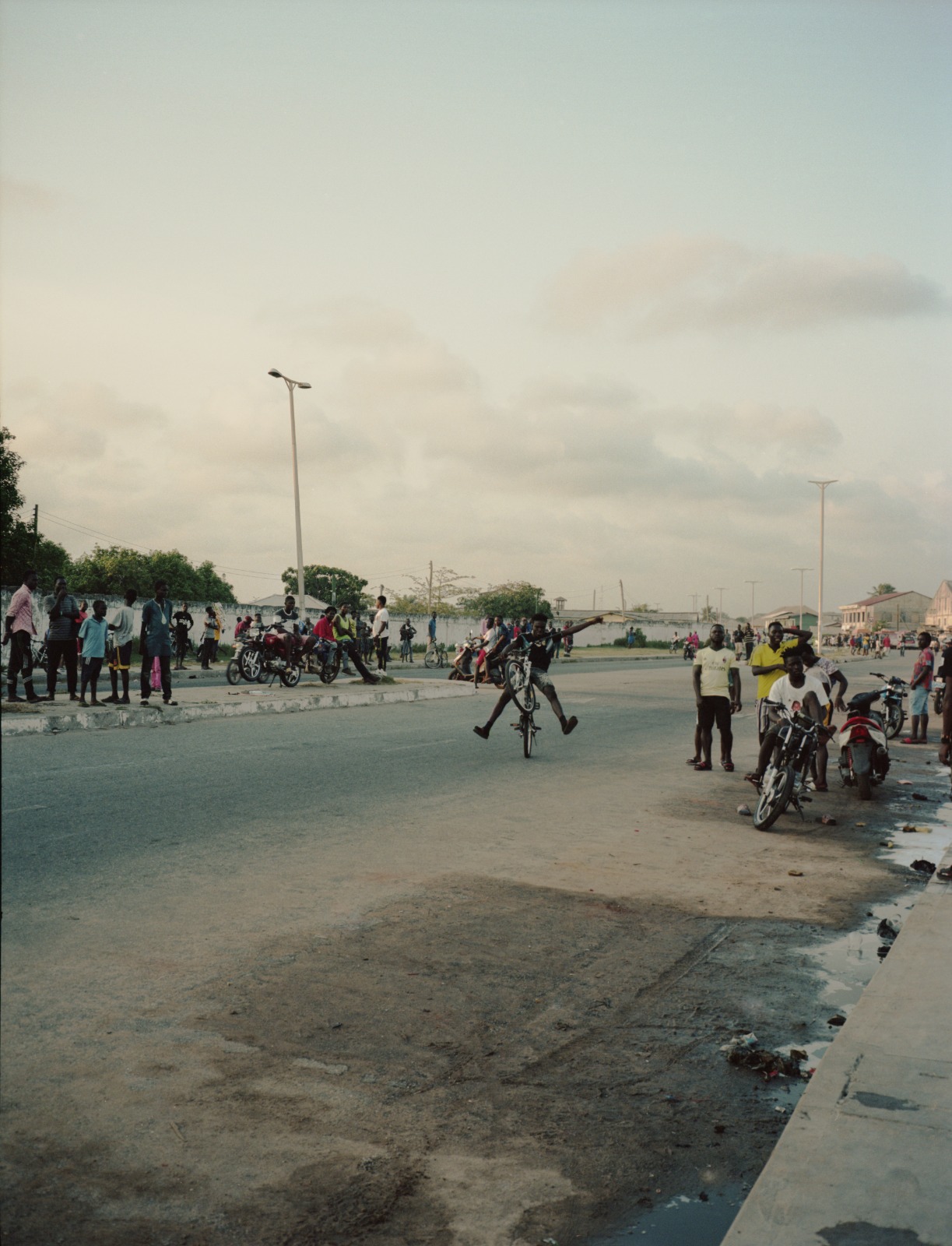 a biker in the middle of the street in ghana with onlookers