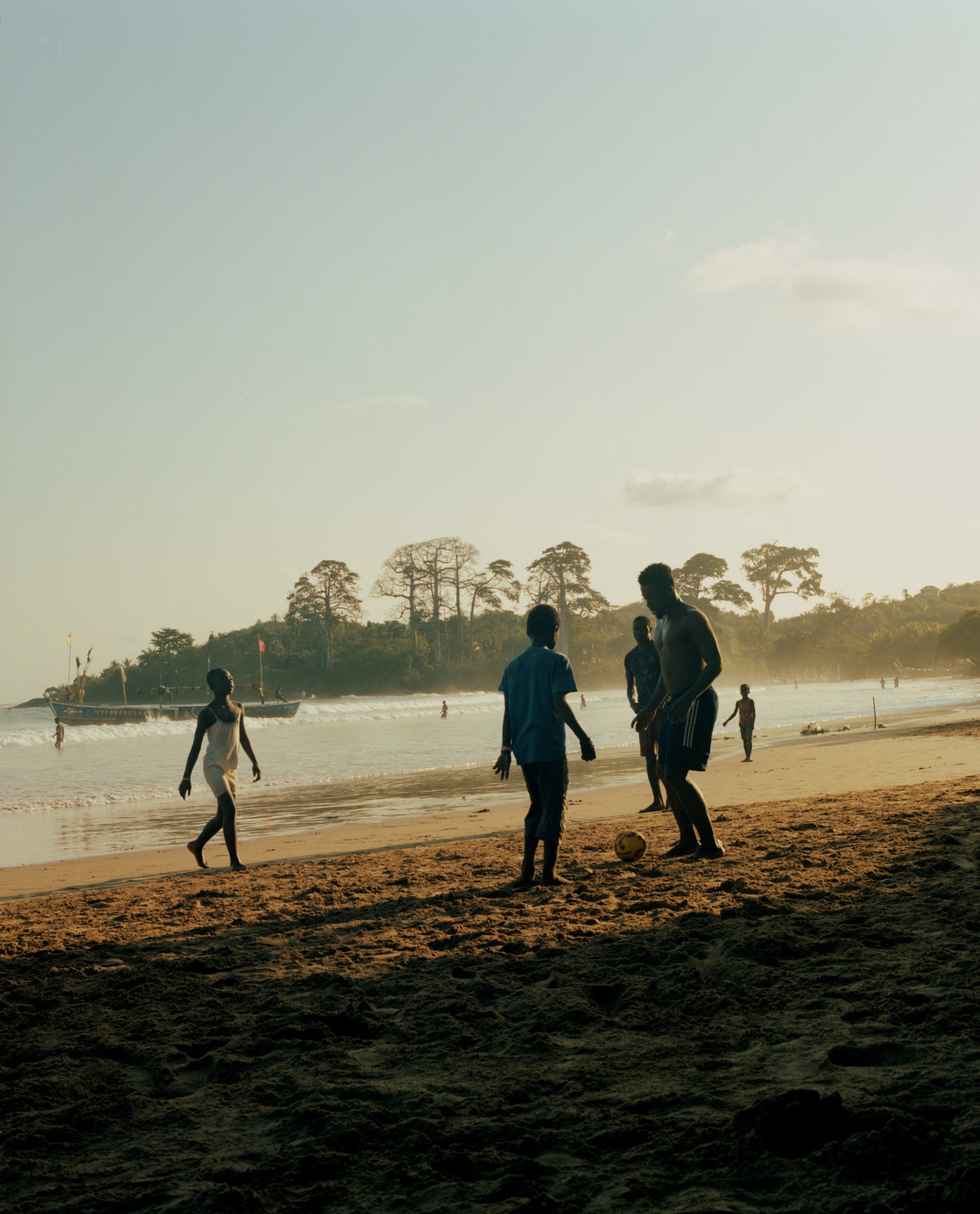 a group of boys playing football on a beach in ghana