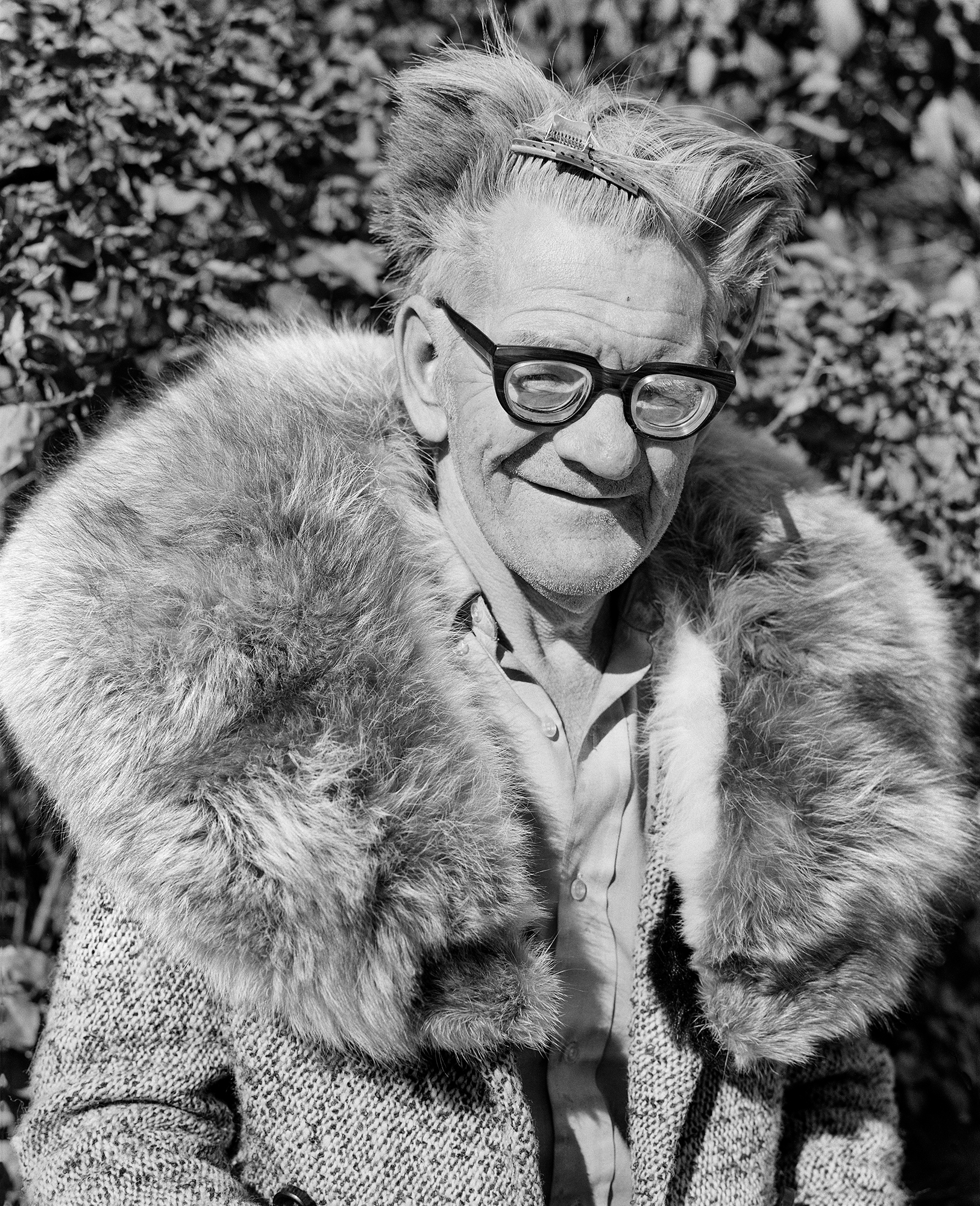 an older man wearing glasses and a fur trimmed coat