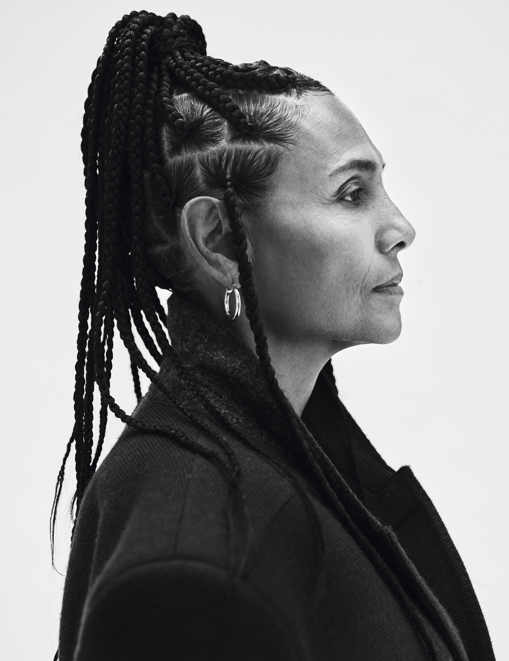 Side profile of Ming Smith wearing a black trench coat and hoop earrings.